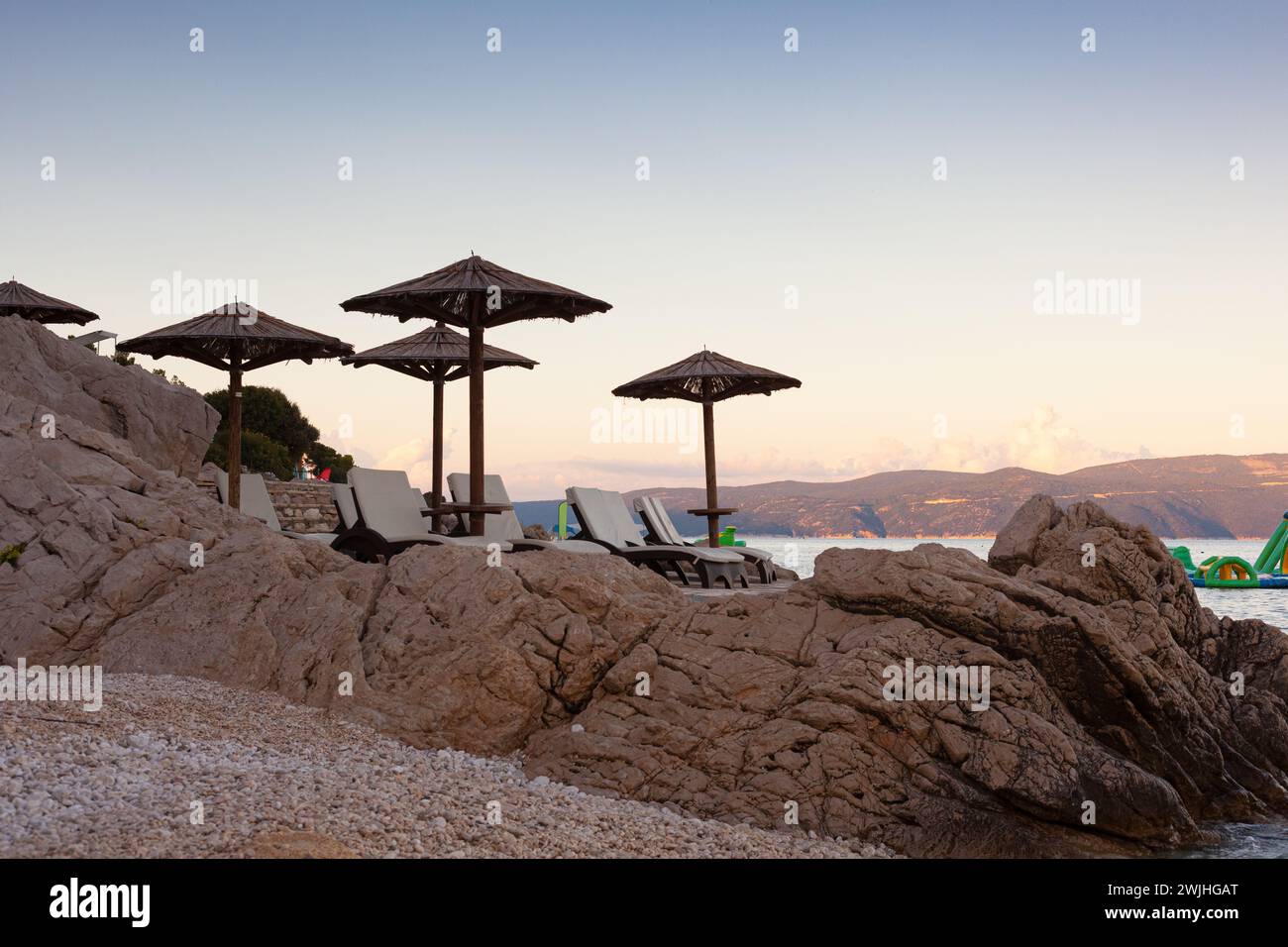 Strohschirme am Strand von Rabac, kroatischer Ferienort an der Kvarner Bucht, direkt südöstlich von Labin in Istrien. Lange ein kleiner Fischerhafen, Rabac Stockfoto