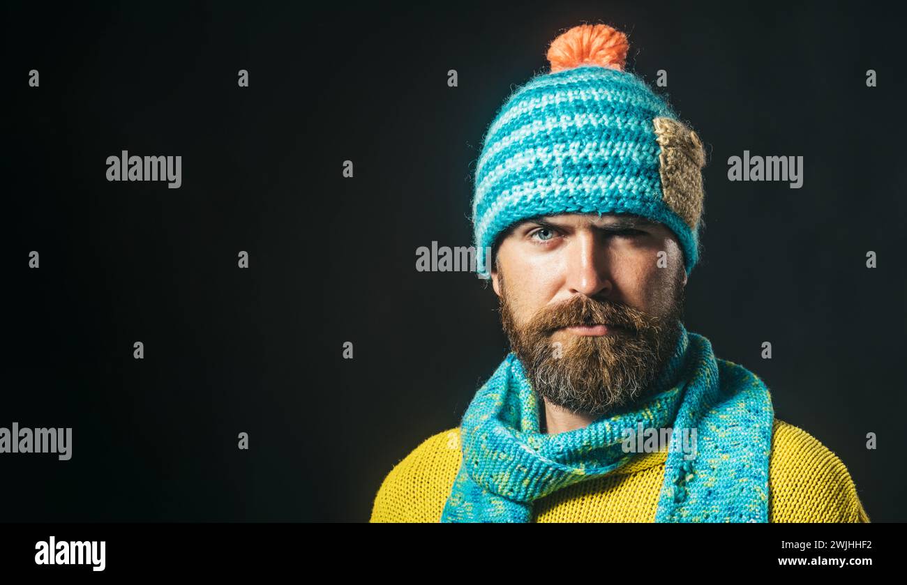 Nahaufnahme Porträt eines ernsten, gutaussehenden Mannes mit Hut und Schal. Attraktiver bärtiger Mann in Strickmütze, Schal und Pullover. Herbst-Winter-Mode. Stilvoll Stockfoto