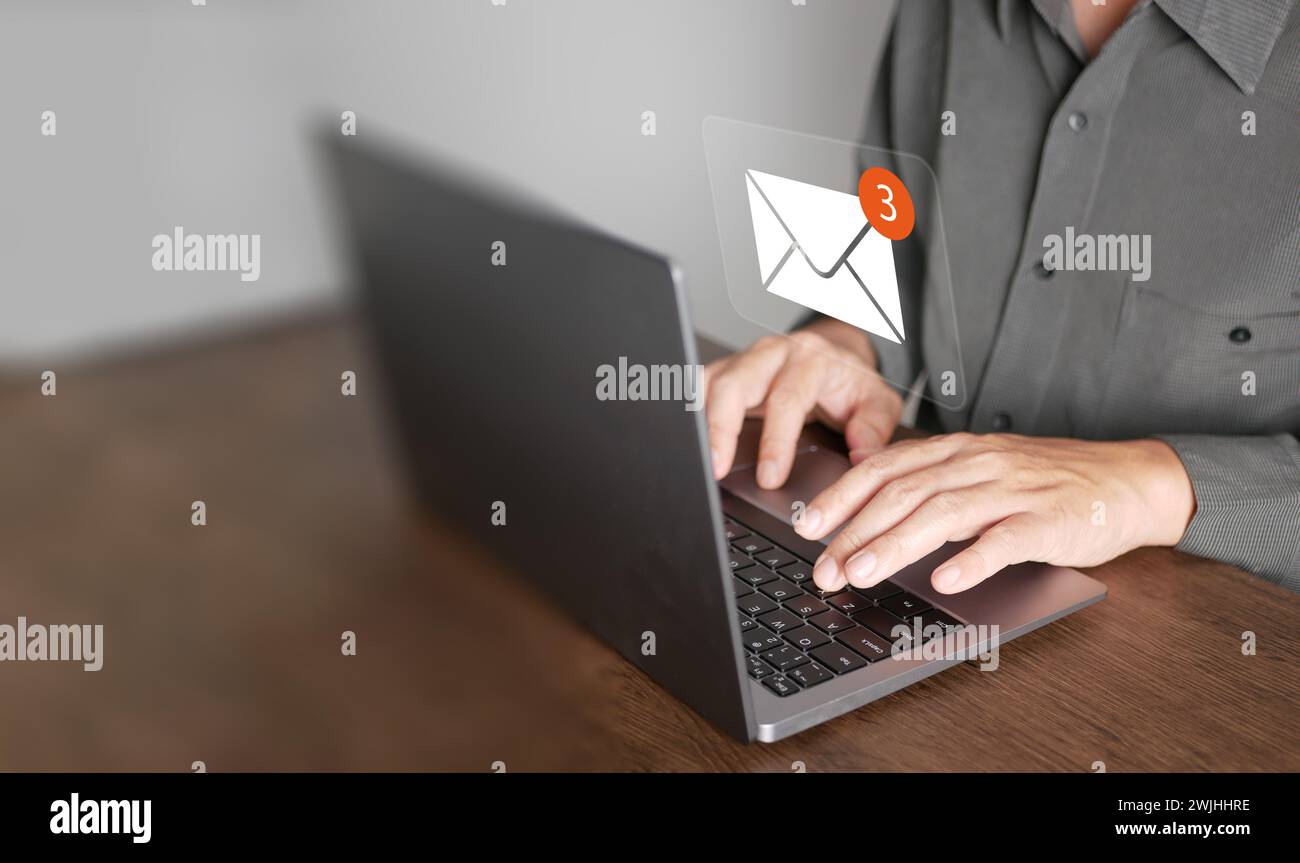 E-Mail- oder E-Mail-Konzept. Ein Mann verwendet Computer-Laptop, um Online-Nachrichten mit E-Mail-Posteingangssymbolen, E-Mail-Marketing und Newslette zu senden und zu empfangen Stockfoto