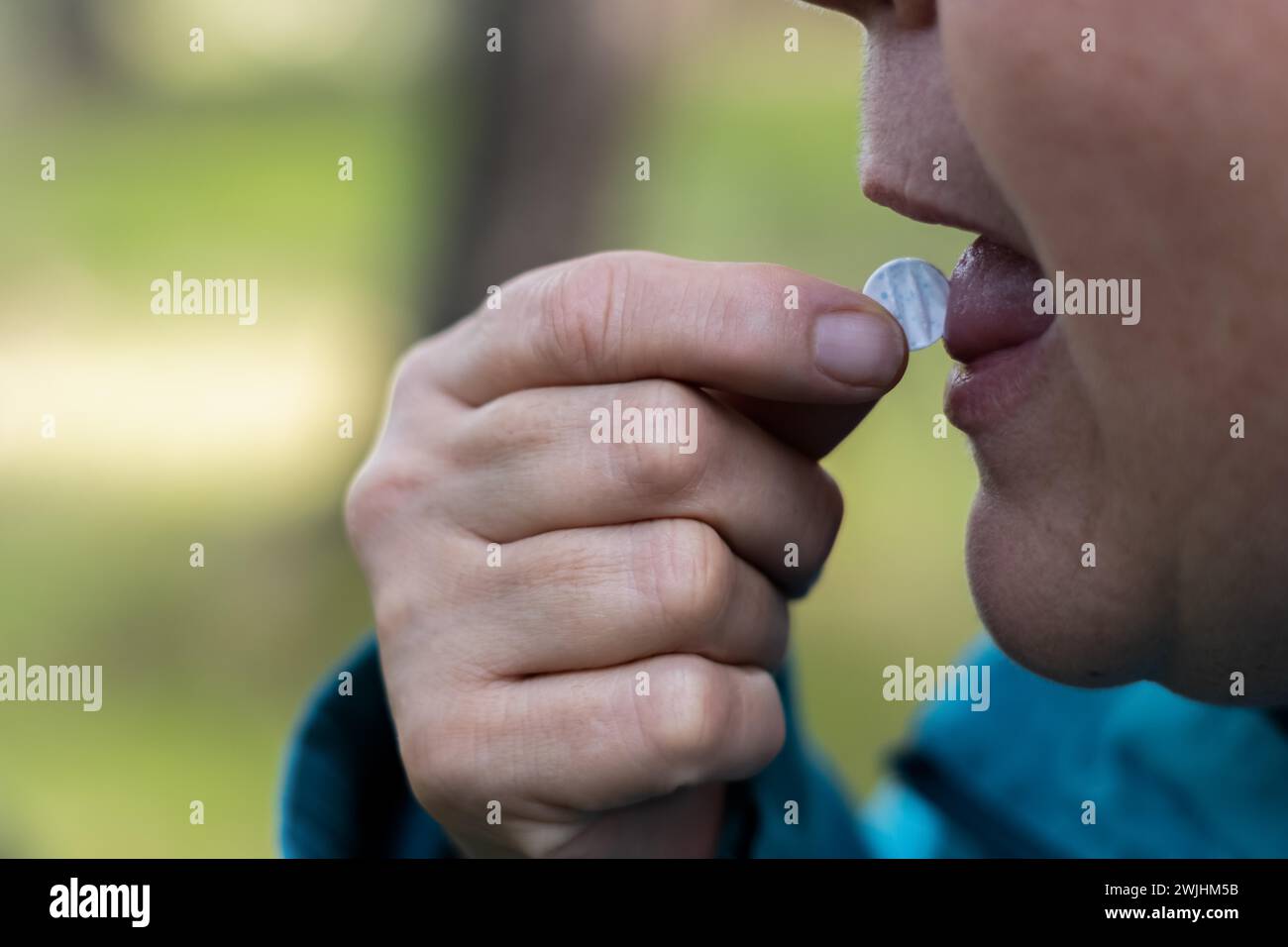 Profilansicht einer Frau, die ihr eine Pille auf die Zunge gibt Stockfoto