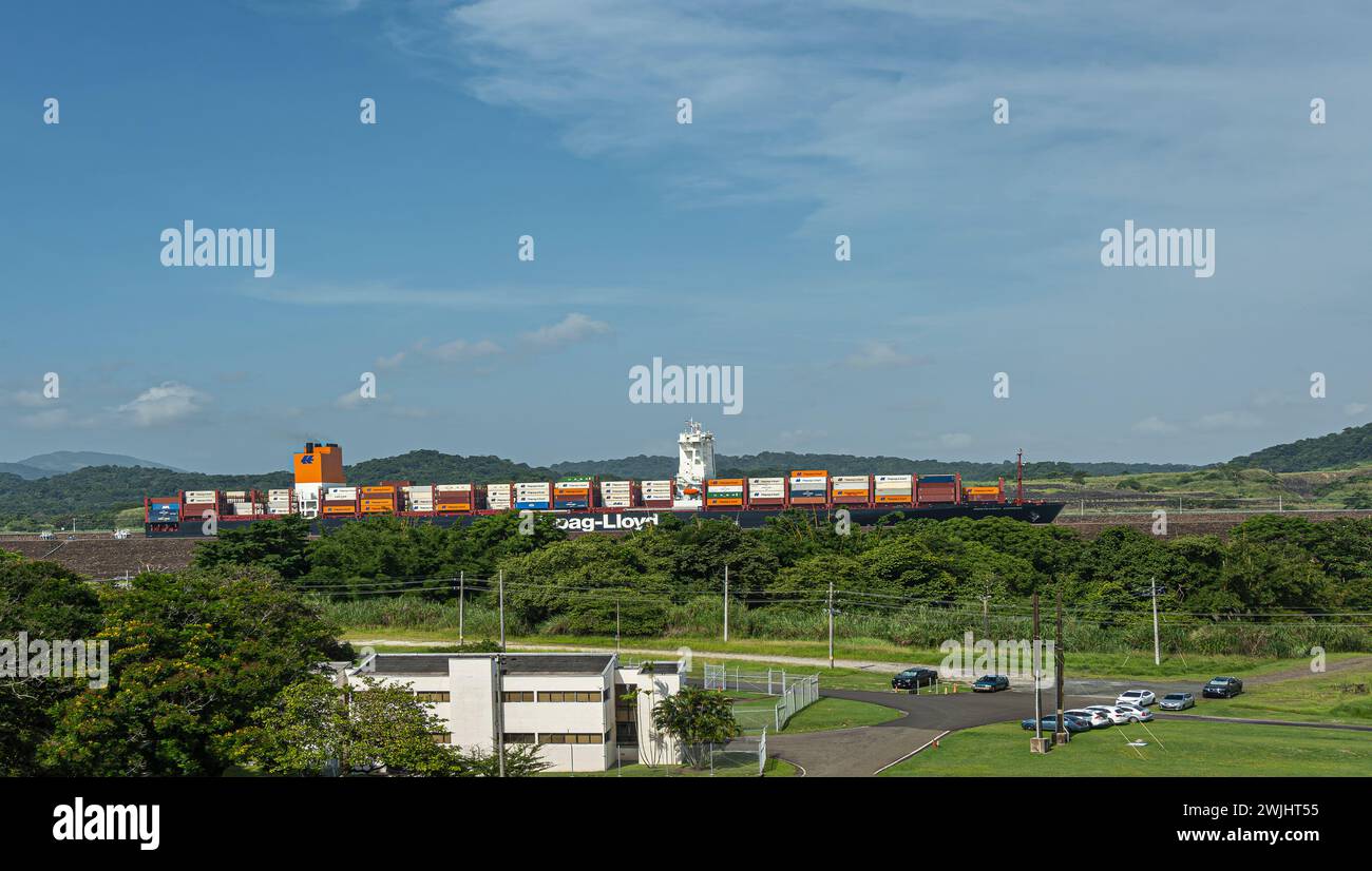 Panamakanal, Panama - 24. Juli 2023: Hapag-Lloyd Containerschiff in neuer Pedro Miguel Schleuse unter blauer Wolkenlandschaft hinter grünen Bäumen. Behälter hinzufügen Col Stockfoto