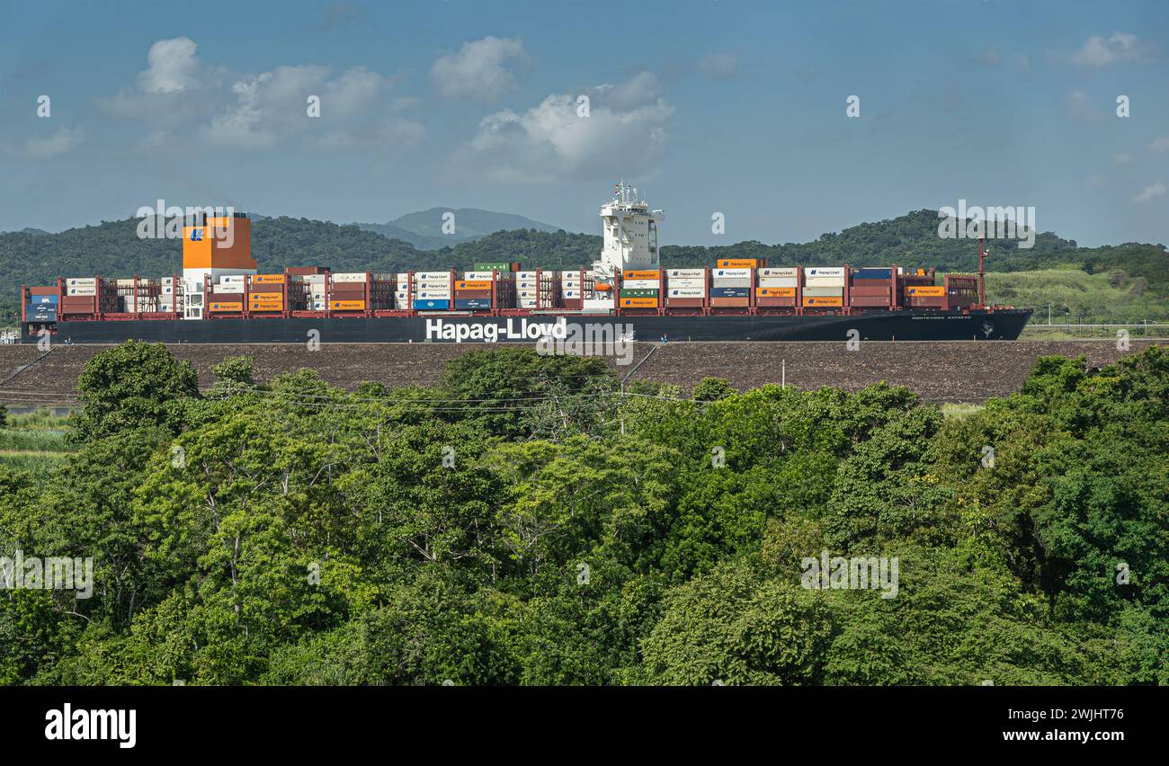 Panamakanal, Panama - 24. Juli 2023: Nahaufnahme, Hapag-Lloyd Containerschiff in neuer Pedro Miguel Schleuse unter blauer Wolkenlandschaft hinter grünen Bäumen. Behälter Stockfoto
