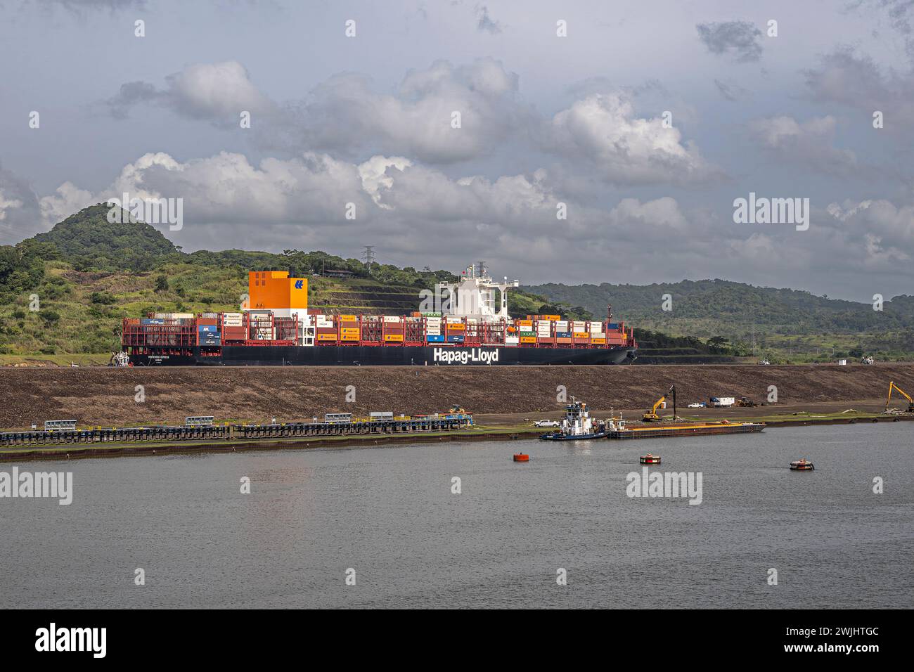 Panamakanal, Panama - 24. Juli 2023: Hapag-Lloyd-Containerschiff nördlich der neuen Schleuse Pedro Miguel unter grauen Wolken. Container fügen Farben hinzu. Arbeiten Sie in Stockfoto