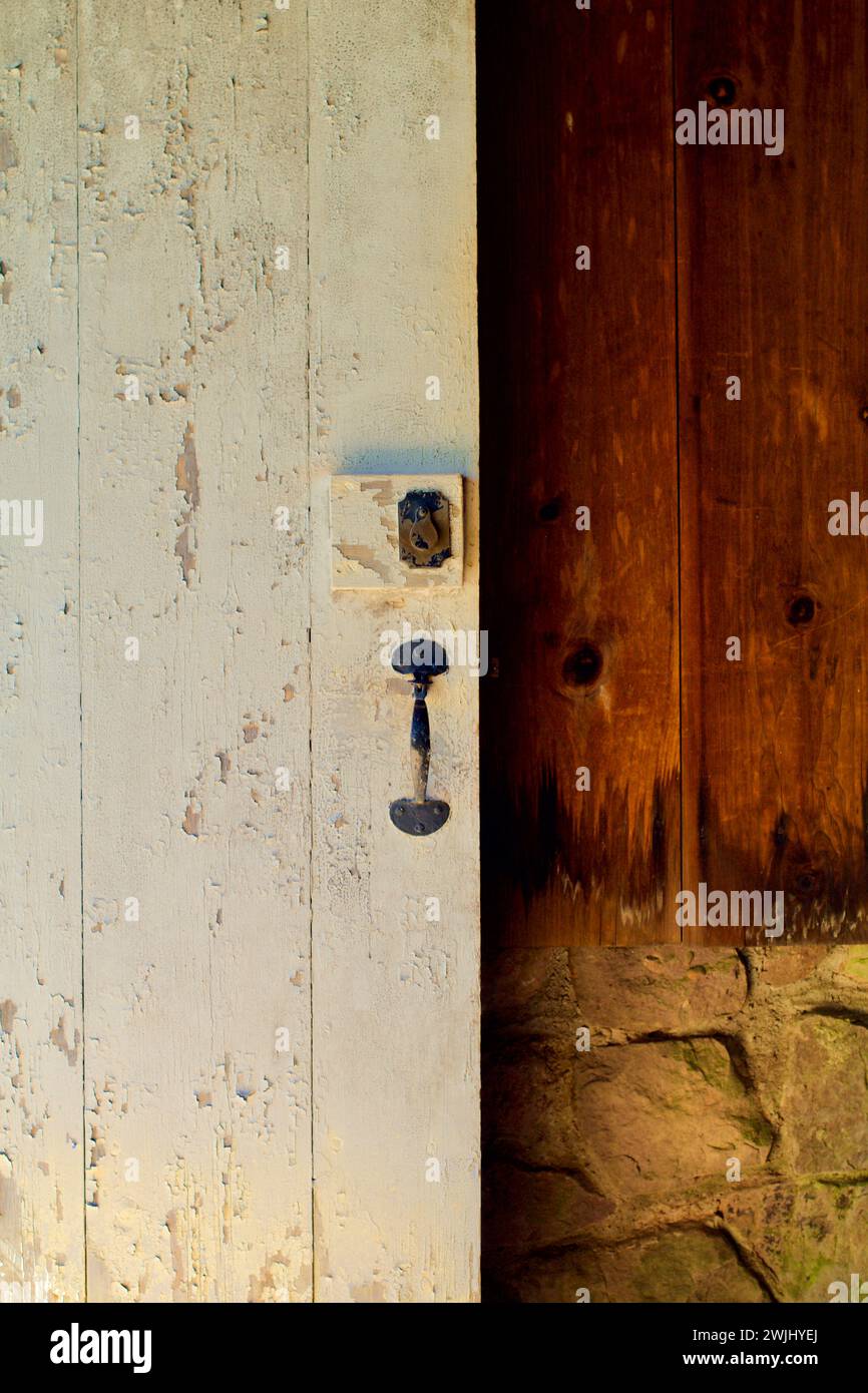 Öffnen Sie die Tür mit einem kunstvollen Riegel gegen eine dunkle Holzwand. Stockfoto