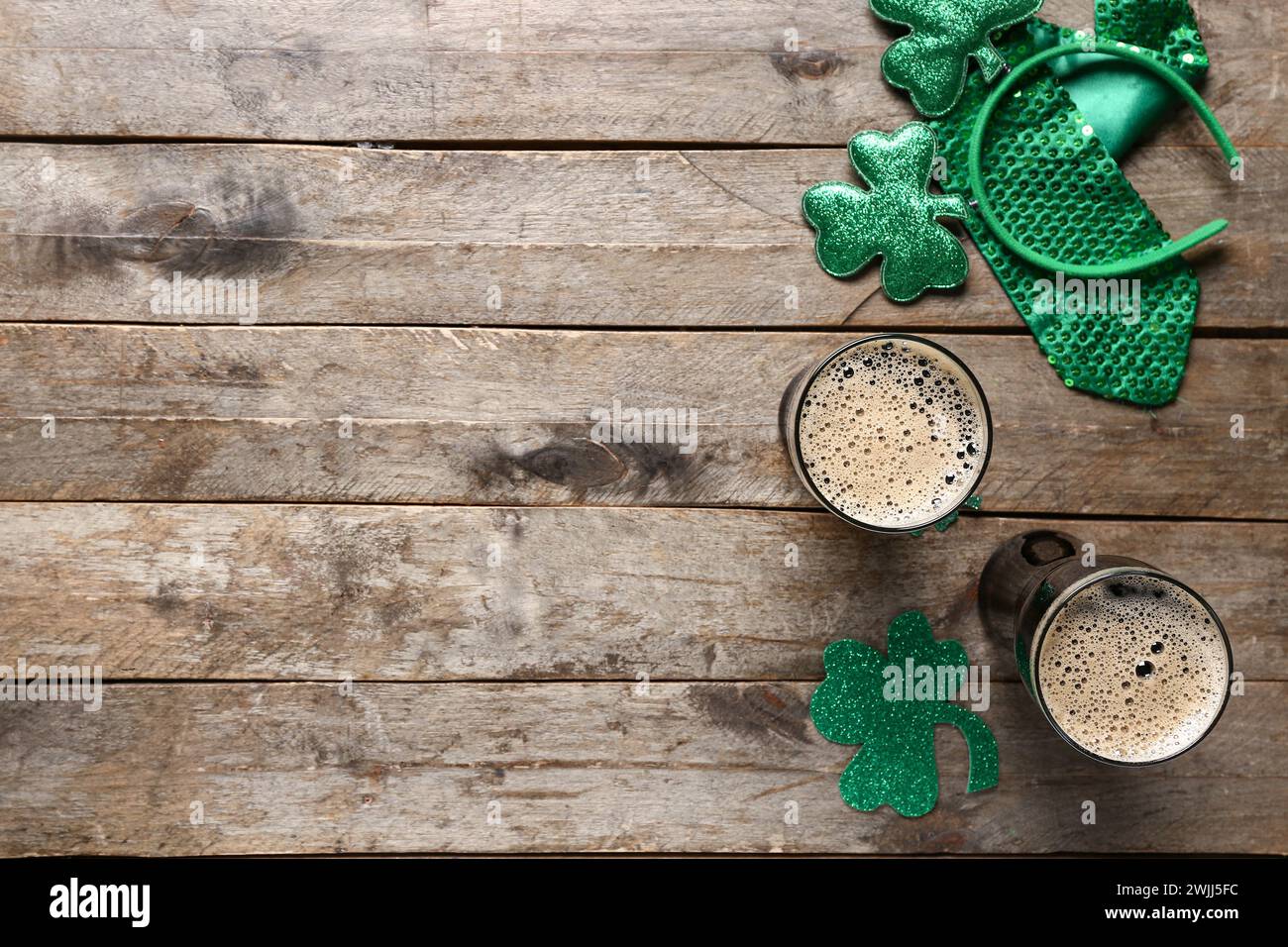Gläser dunkles Bier mit Krawatte und Dekor für St. Patrick's Day-Feier auf hölzernem Hintergrund Stockfoto