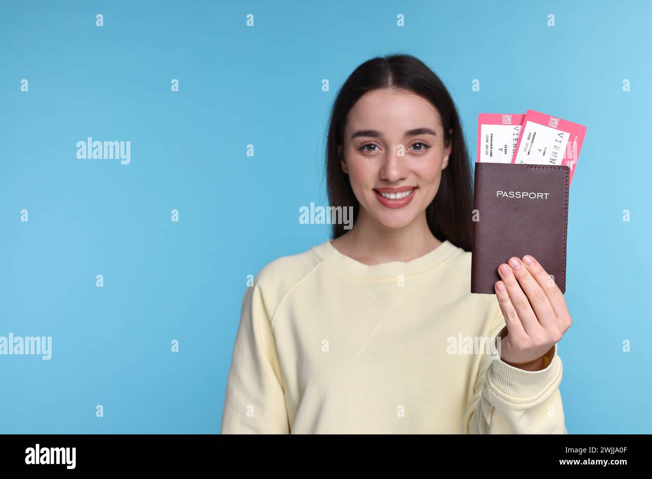 Glückliche Frau, die Pass und Tickets auf hellblauem Hintergrund zeigt, selektiver Fokus. Leerzeichen für Text Stockfoto