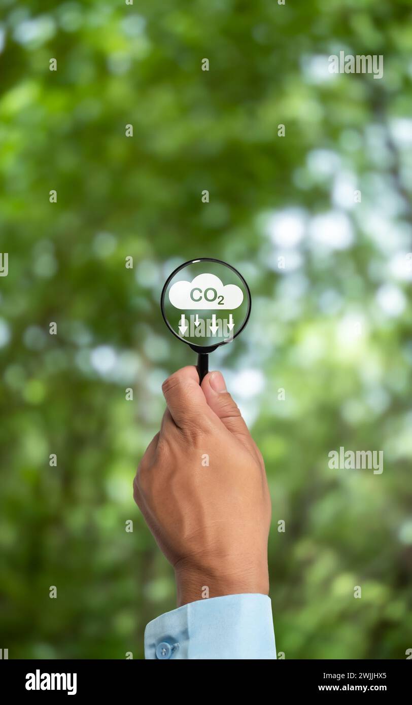 Eine saubere und freundliche Umwelt ohne Kohlendioxidemissionen, Lupe in der Hand mit Symbol zur CO2-Reduktion innen, CO2-Gutschrift an Limi Stockfoto
