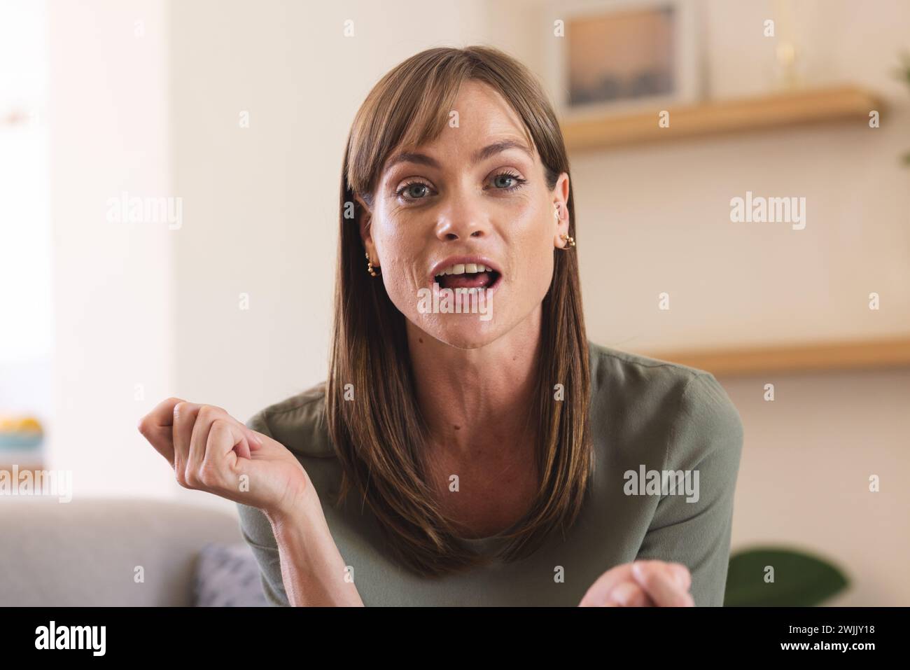 Eine weiße Frau mittleren Alters scheint bei einem Videoanruf mit einer ausdrucksstarken Geste zu sprechen Stockfoto