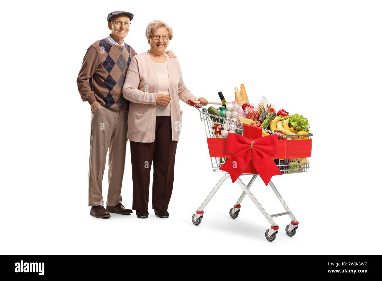 Porträt eines älteren Paares in voller Länge, das mit einem Einkaufswagen posiert, der mit einem roten Band gebunden ist, isoliert auf weißem Hintergrund Stockfoto