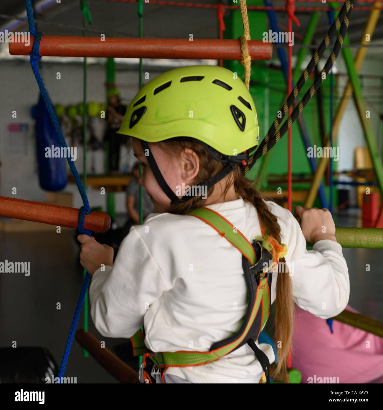 Aktive und körperliche Entwicklung des Kindes, das Mädchen passiert die Seilbahn im Spielzimmer. Stockfoto