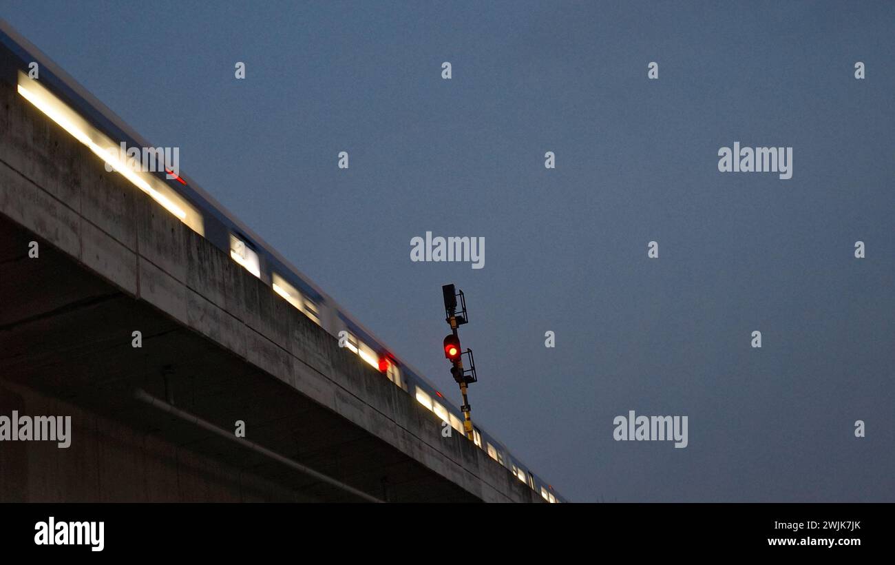 Unter dem Schleier der Nacht durchquert der Zug der Stadt Medan die Dunkelheit, seine Lichter malen Lichtstreifen, ein nächtliches Spektakel. Stockfoto