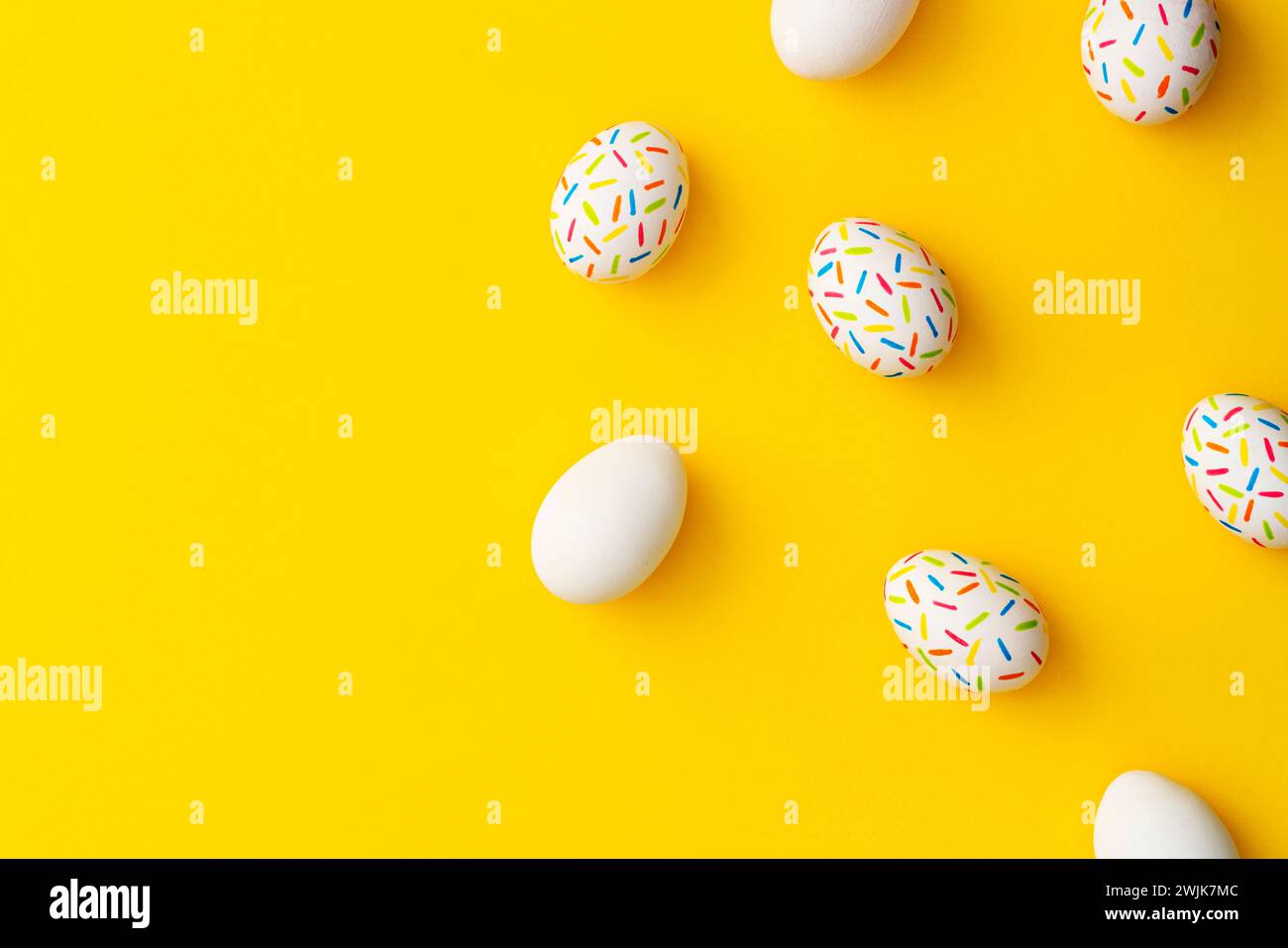 Bestreuen Sie bunte ostereier auf gelbem Hintergrund. Direkt über der Tischplatte. Stockfoto