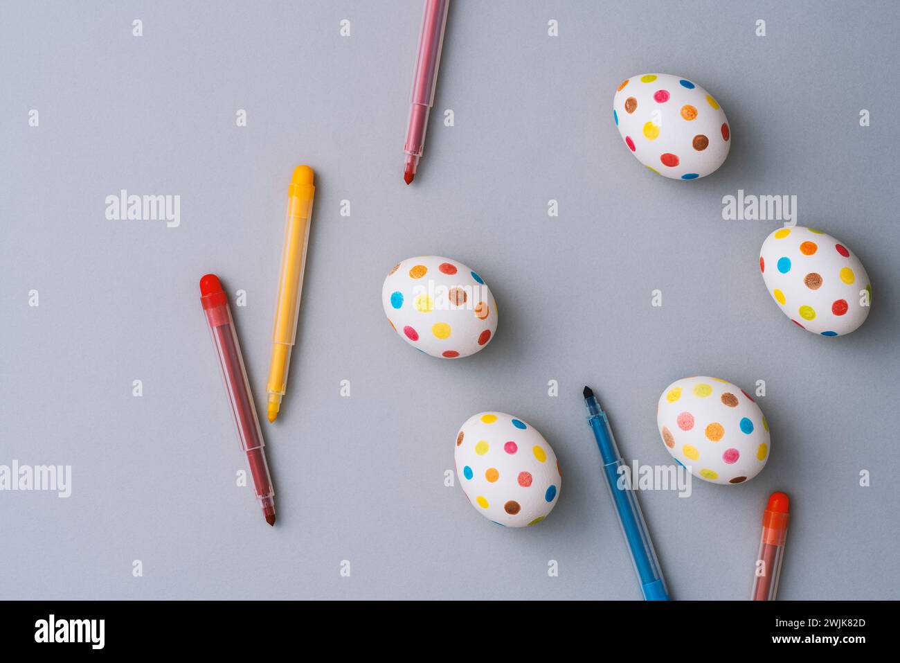 Bunte ostereier mit Farbstiften auf grauem Hintergrund. Direkt über der Tischplatte. Stockfoto