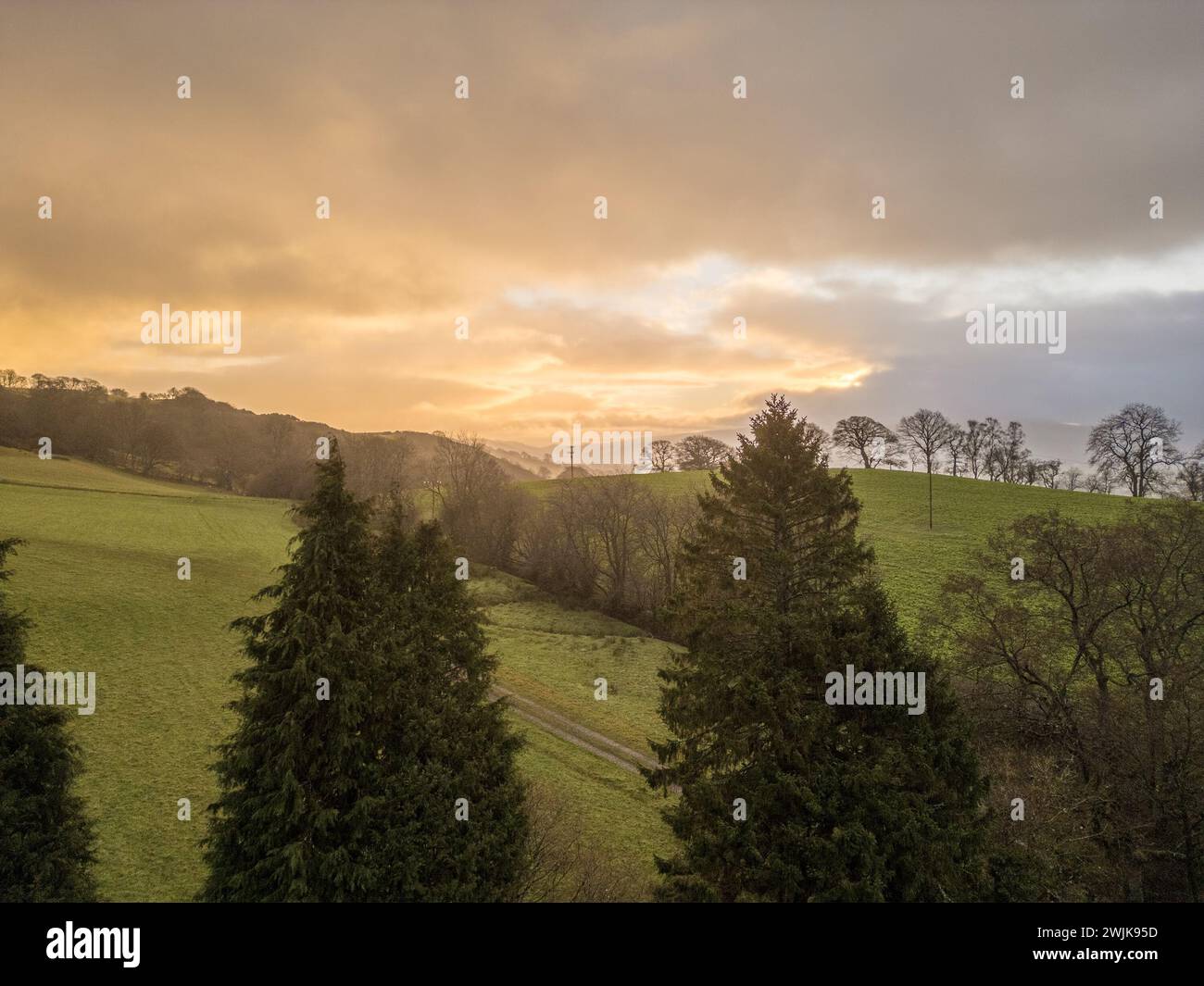 Sonnenaufgang über den Hügeln von Denbighshire, Wales, wenn die Sonne durch dunkle Wolken bricht und leichter Regen über die Landschaft fällt. Stockfoto