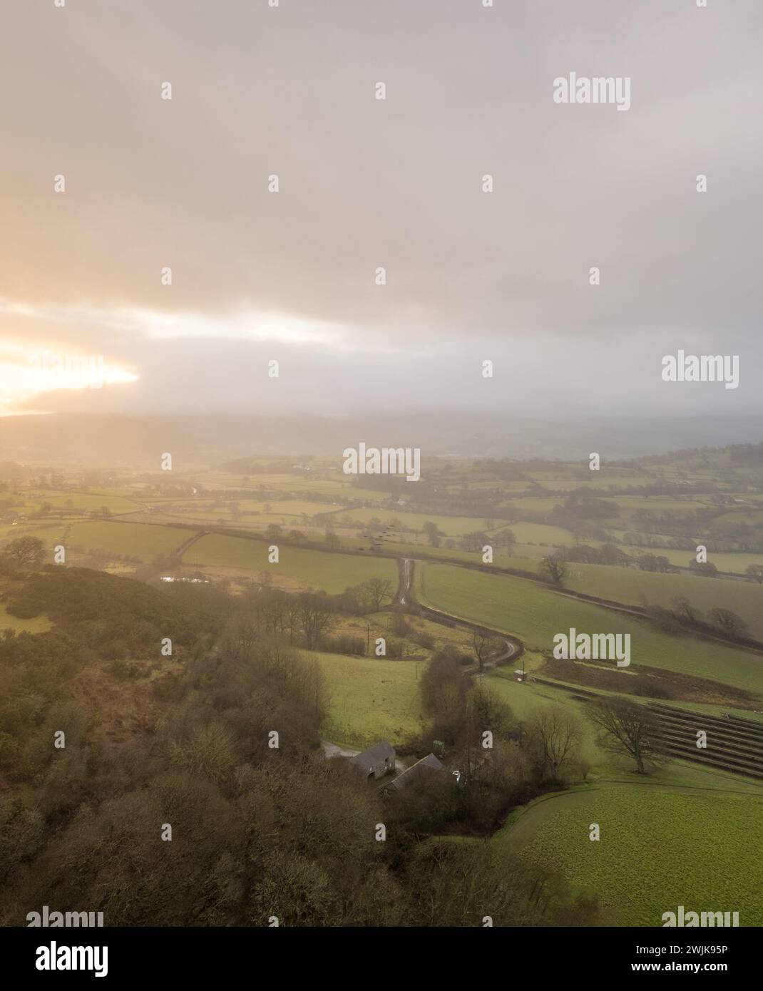 Sonnenaufgang über den Hügeln von Denbighshire, Wales, wenn die Sonne durch dunkle Wolken bricht und leichter Regen über die Landschaft fällt. Stockfoto