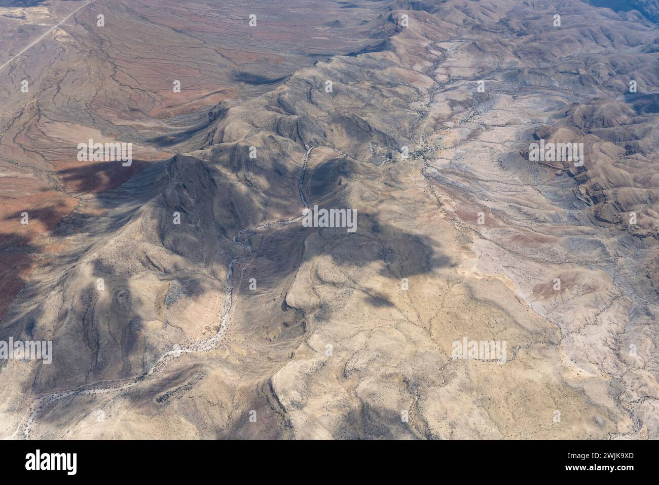 Luftlandschaft mit Gebirgszügen in hügeliger Wüste, aufgenommen von einem Segelflugzeug im hellen Licht des späten Frühlings östlich von Bullsport, Namibia, Afrika Stockfoto