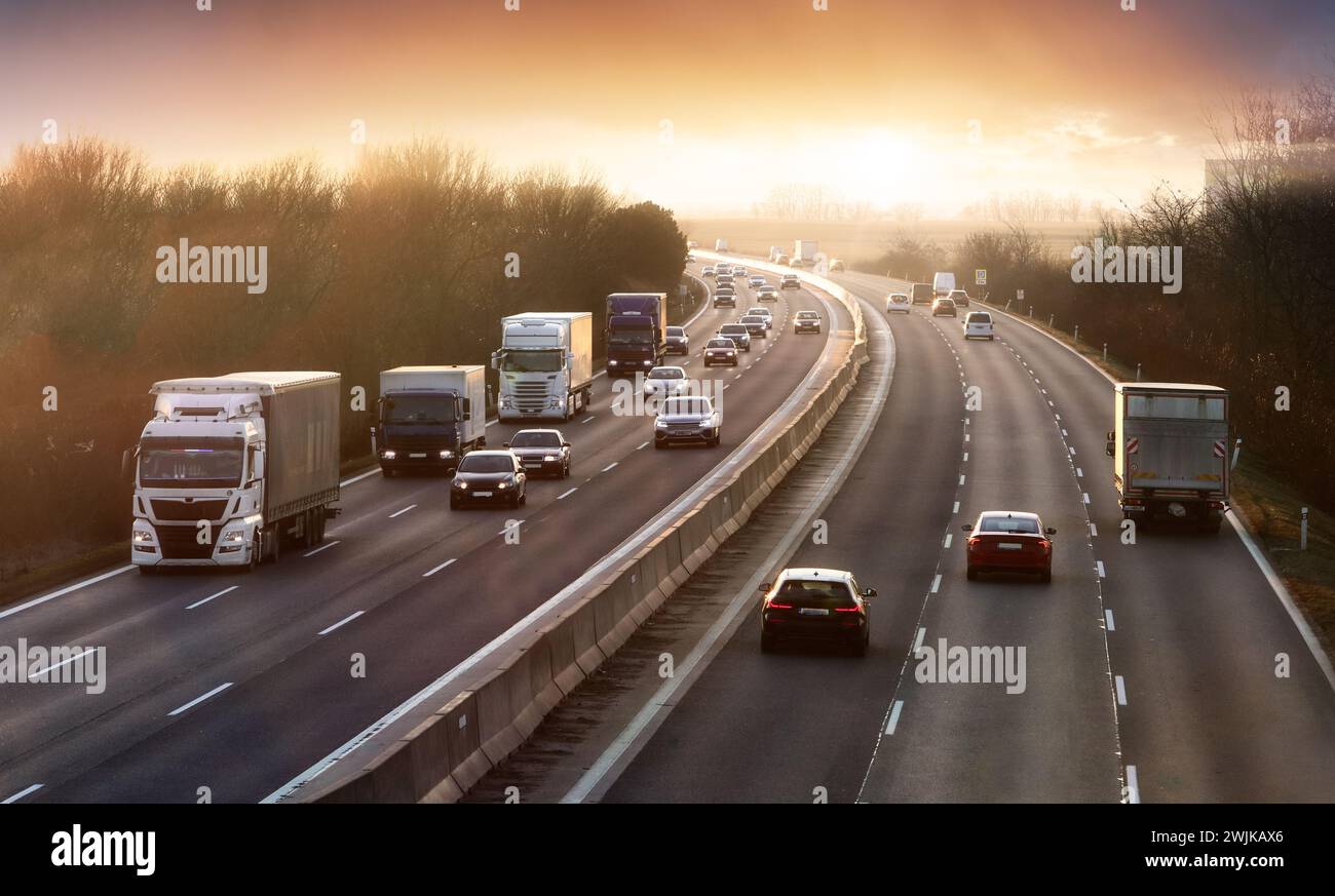Autobahntransport mit Autos und LKW, Verkehr bei Sonnenuntergang Stockfoto