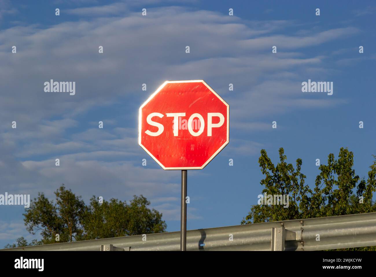 Rotes Stoppschild mit blauem Himmel und Wolken Hintergrund der Straße. Stockfoto