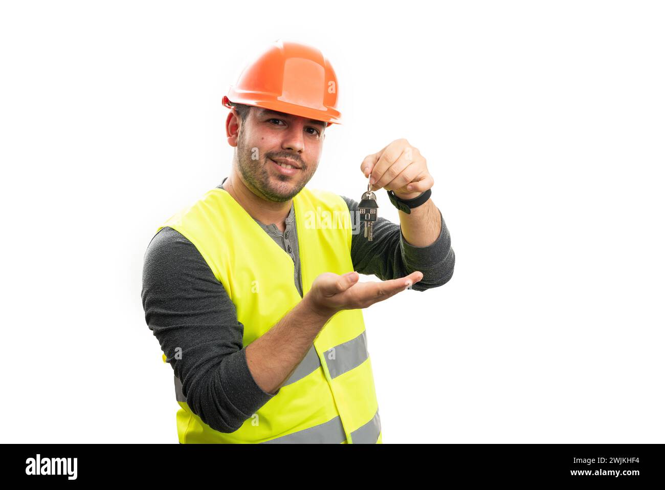 Freundlicher erwachsener Baumeister Mann in Arbeitskleidung fluoreszierende Weste und orange Sicherheit Hardhat präsentiert Hauptschlüssel mit Palme isoliert auf weißem Hintergrund Stockfoto