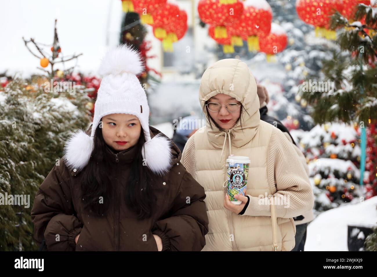 Zwei asiatische Mädchen, die auf dem Hintergrund der chinesischen Neujahrsdekoration in der Winterstadt laufen Stockfoto