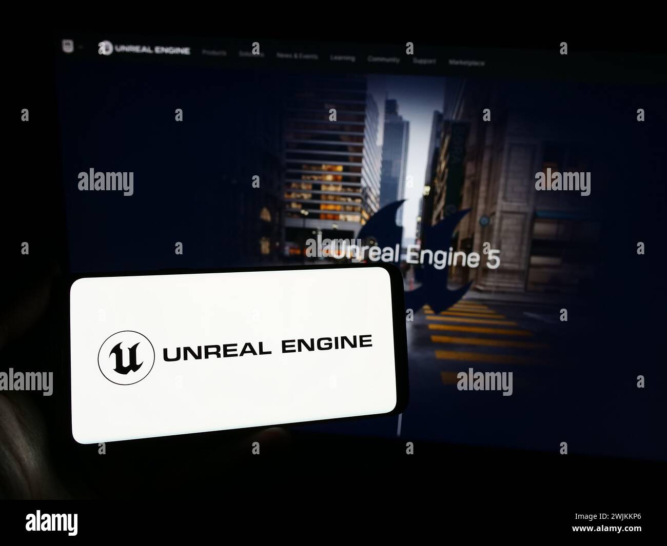 Person, die ein Smartphone mit dem Logo der 3D-Spielesoftware Unreal Engine (Epic Games) vor der Website hält. Schwerpunkt auf dem Display des Telefons. Stockfoto