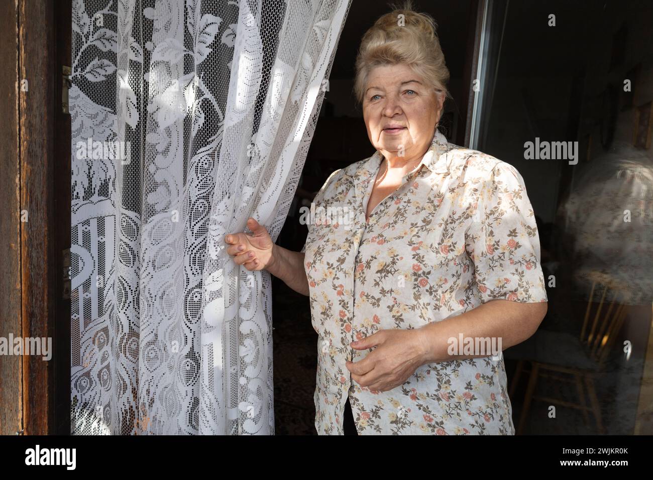 Eine ältere Frau steht am Fenster. Porträt, aktives Alter Stockfoto