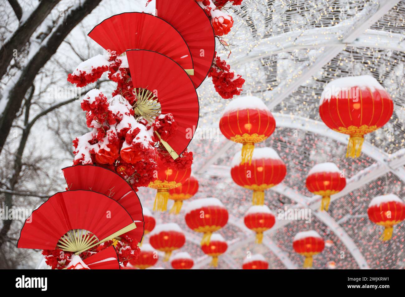 Chinesische Neujahrsdekoration in der Winterstadt. Festliche Gasse mit roten Papierfächern und Laternen Stockfoto