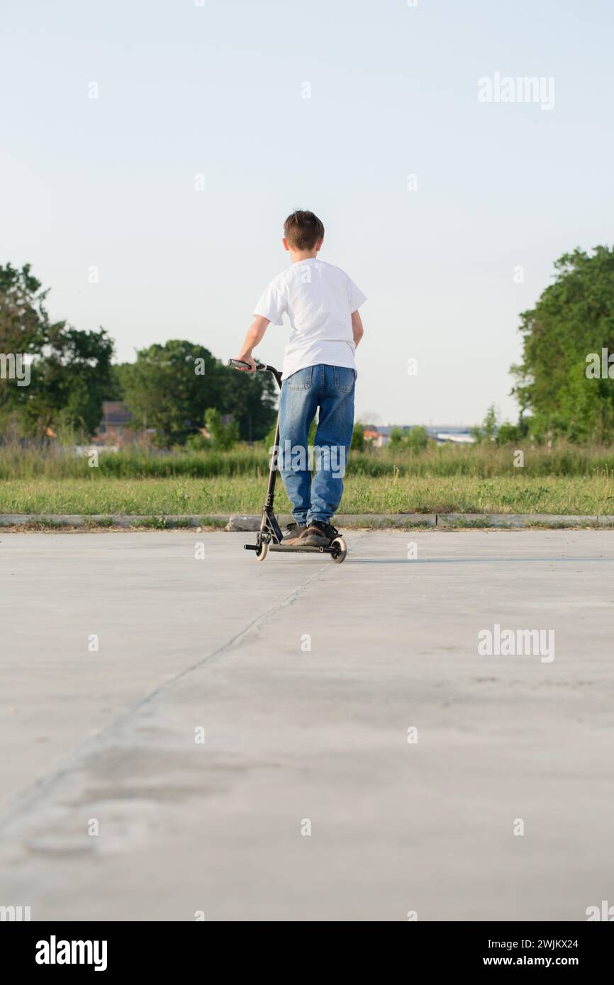 Ein Teenager springt auf einen Roller Stockfoto