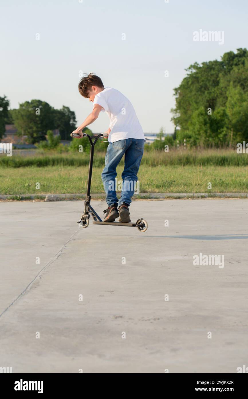Ein Teenager springt auf einen Roller Stockfoto
