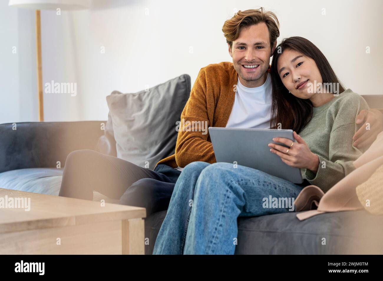 Erwachsenes Paar, das auf der Kamera sitzt und ein digitales Tablet nutzt Stockfoto