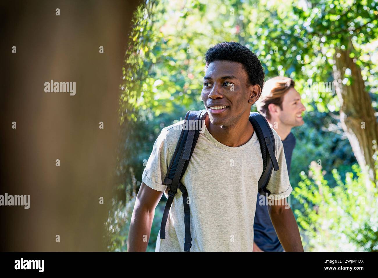 Junger erwachsener Mann mit Rucksack beim Wandern mit Freunden Stockfoto