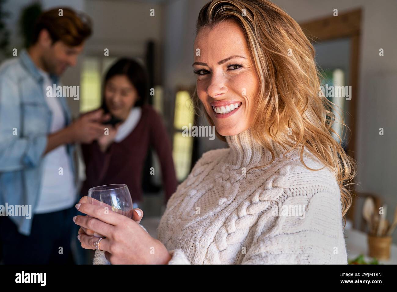 Fröhliche Frau, die in die Kamera blickt und Weinglas hält Stockfoto