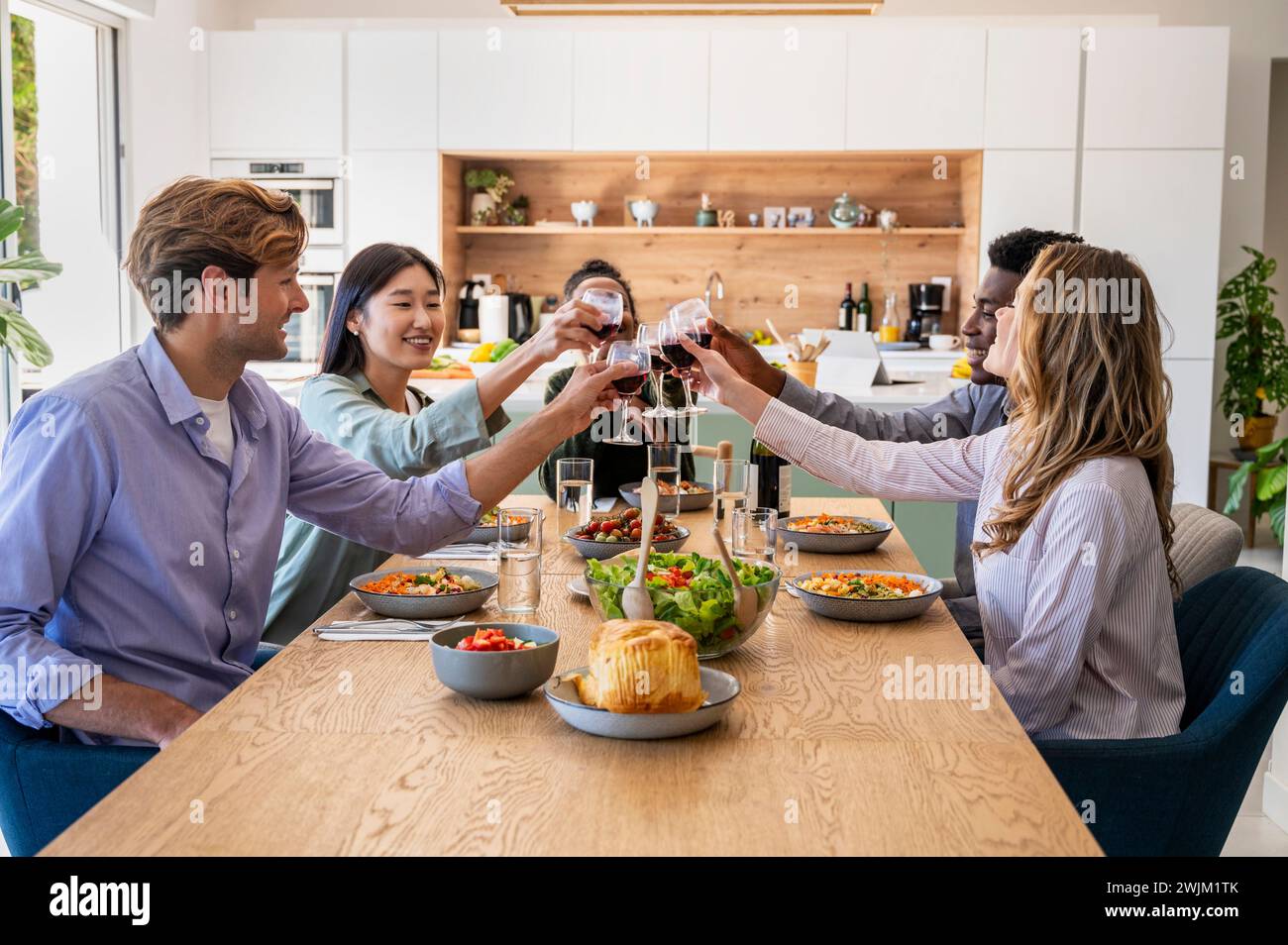 Gruppe von Freunden, die während des Abendessens mit Weingläsern toasten Stockfoto