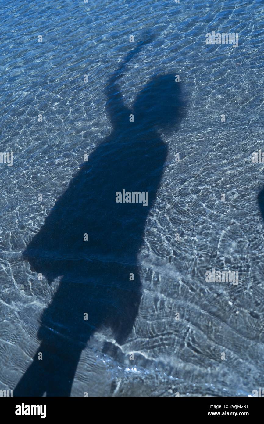 Schatten einer nicht identifizierten Person auf blauem Wasser Stockfoto