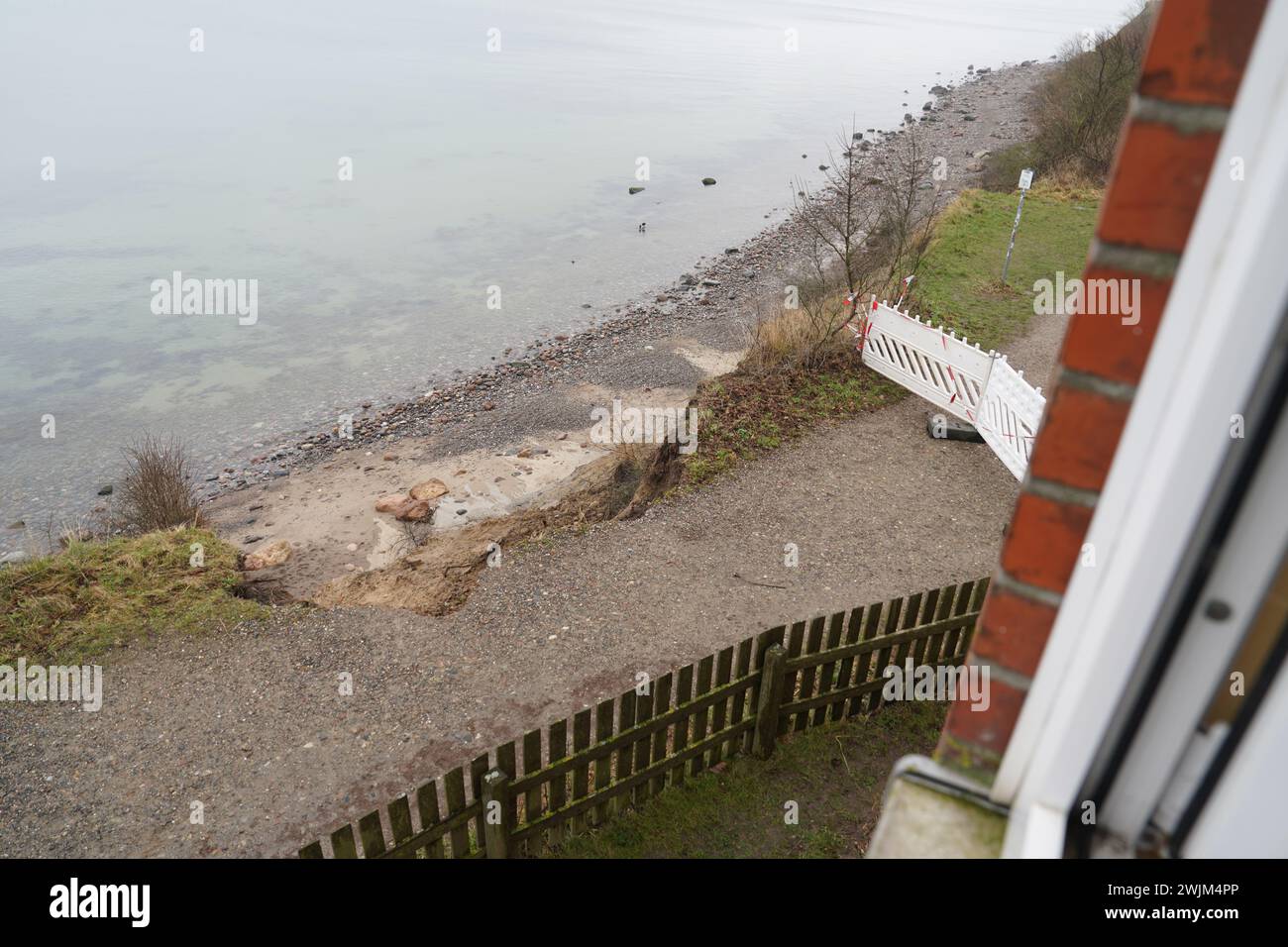 PRODUKTION - 14. Februar 2024, Schleswig-Holstein, Lübeck-Travemünde: Blick aus einem Fenster im zweiten Stock des Jugendzentrums Haus Seeblick der Jugendorganisation SJD - die Falken auf den Rand der Klippe im Stadtteil Brodten an der Ostsee. Das Jugendzentrum Haus Seeblick, das direkt an den Brodtenfelsen liegt, ist nach einem weiteren Klippeneinsturz nun für Kinder- und Jugendarbeit geschlossen. Nur gut vier Meter liegen zwischen einer Ecke des 'Haus Seeblick' und dem Abgrund. Ende Januar fiel ein Baum am Rande und hinterließ ein Loch im Fußweg vor der Tür Stockfoto