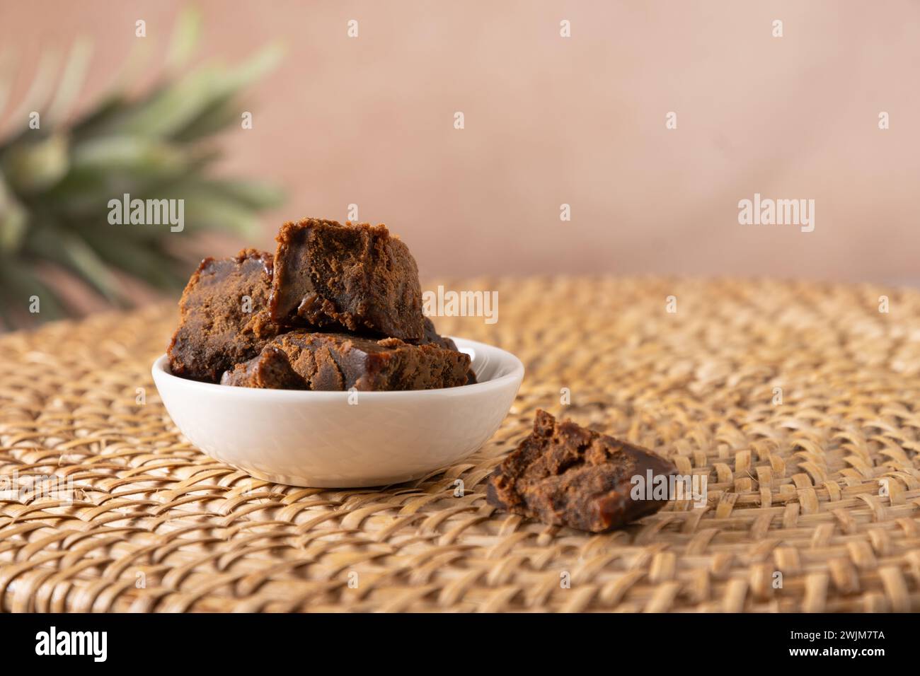 Kithul-Zierfräse und Treakle-natürliches Süßungsmittel in weißer Schüssel auf traditionellem Korbblech. Nahaufnahme. Vegane Nahrung mit niedrigem glykämischen Index. Superfood. Stockfoto