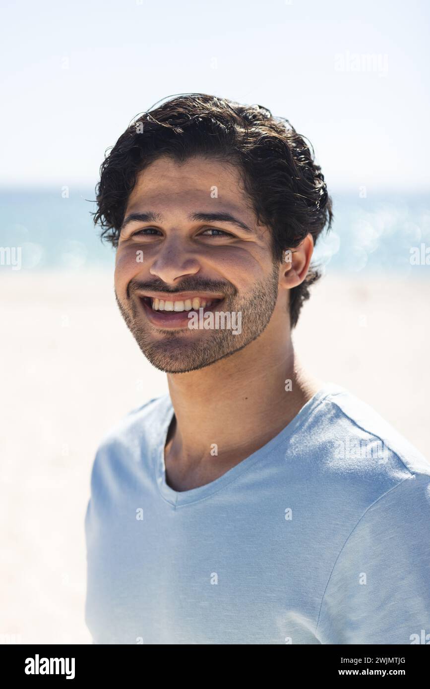 Junger Mann aus der Rasse lächelt hell draußen am Strand Stockfoto