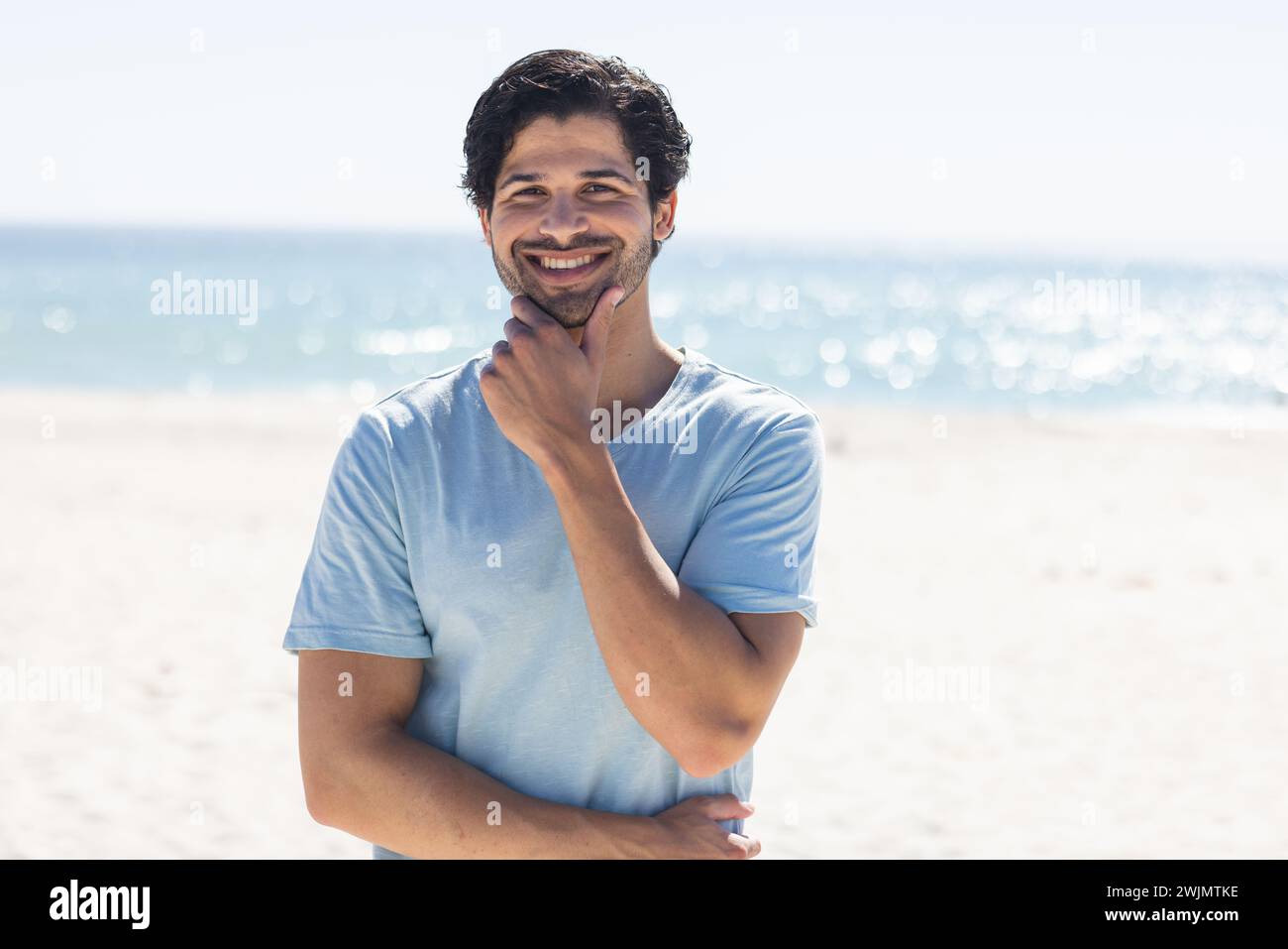 Ein junger, birassischer Mann lächelt am Strand Stockfoto