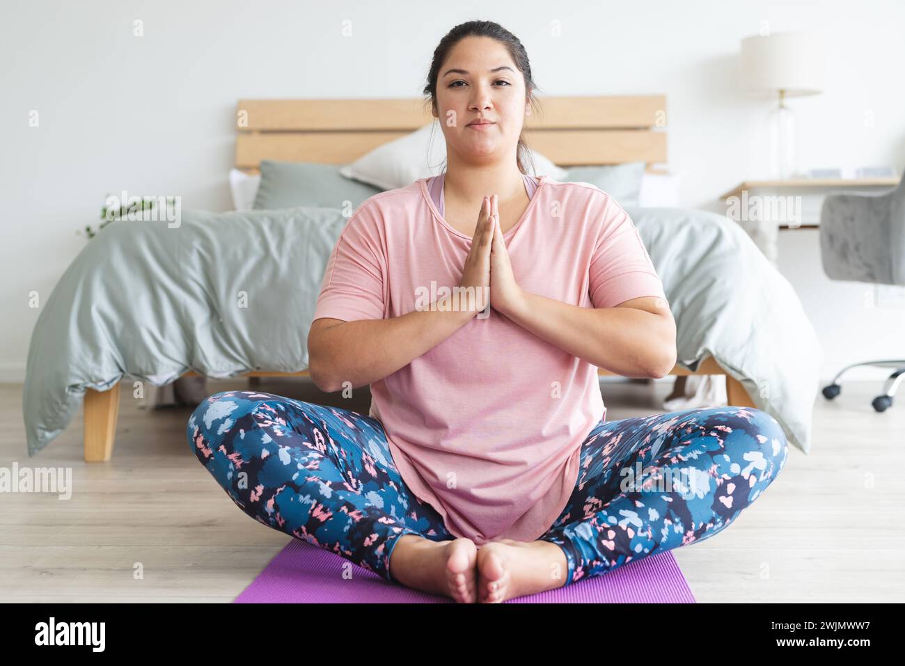 Eine junge Frau in Übergröße praktiziert Yoga zu Hause Stockfoto