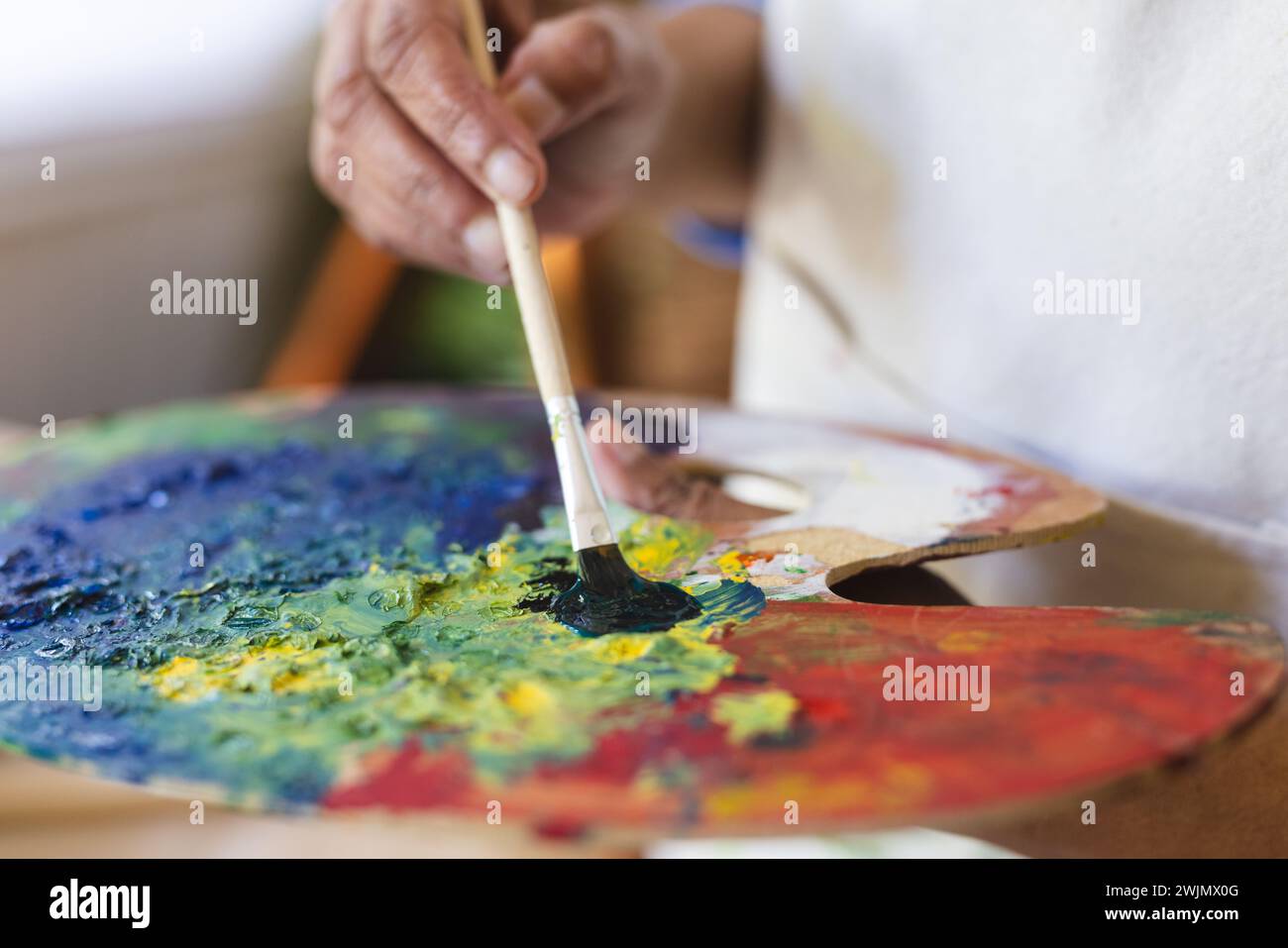 Der Künstler mischt zu Hause lebendige Farben auf einer Palette Stockfoto