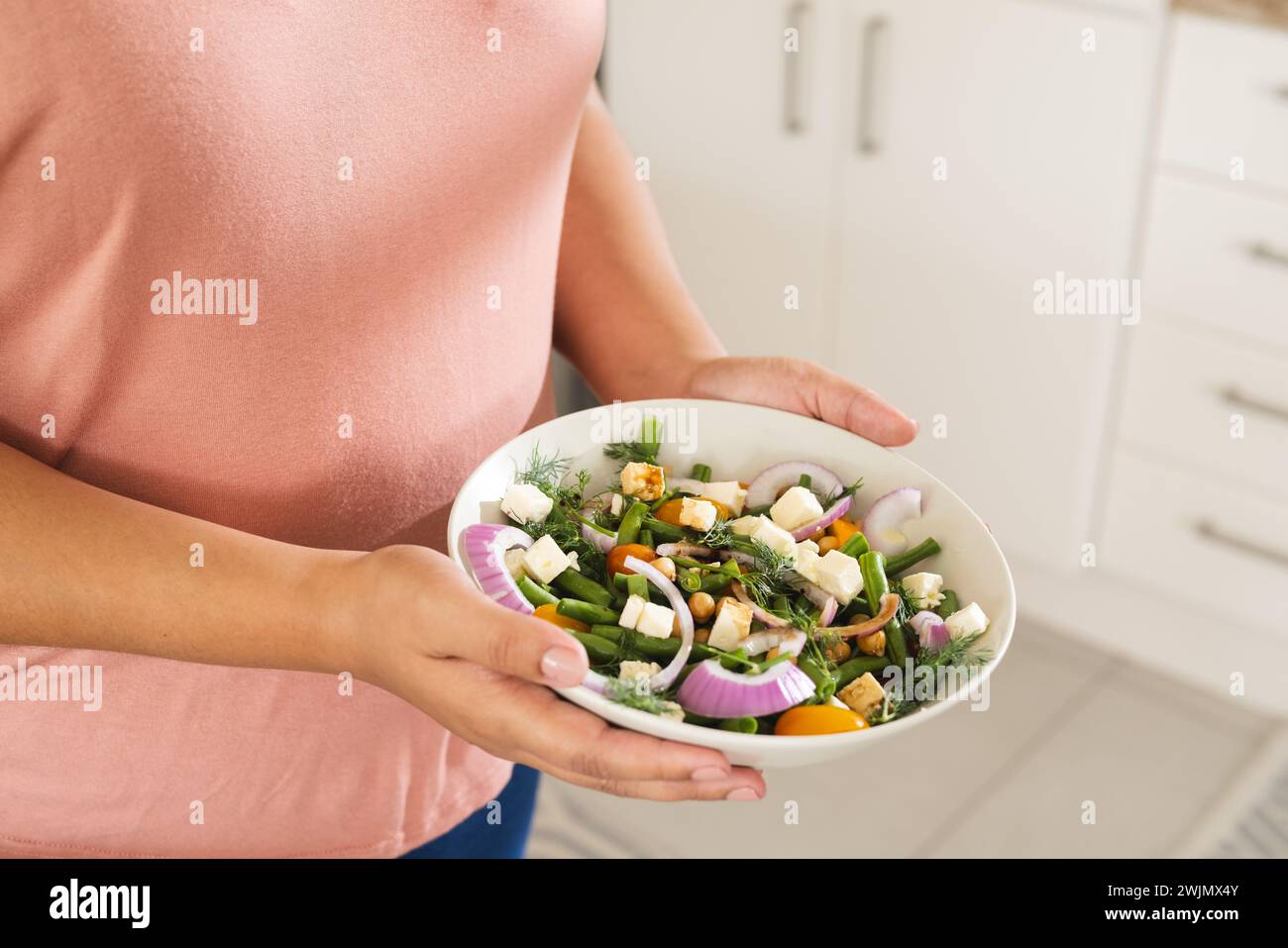 Eine Person hält eine frische Salatschüssel in der Küche Stockfoto
