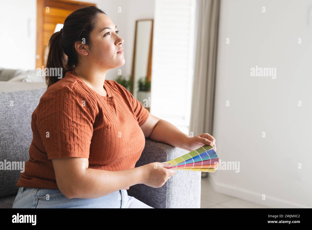 Eine junge Frau in Übergröße untersucht Farbmuster zu Hause unverfälscht Stockfoto