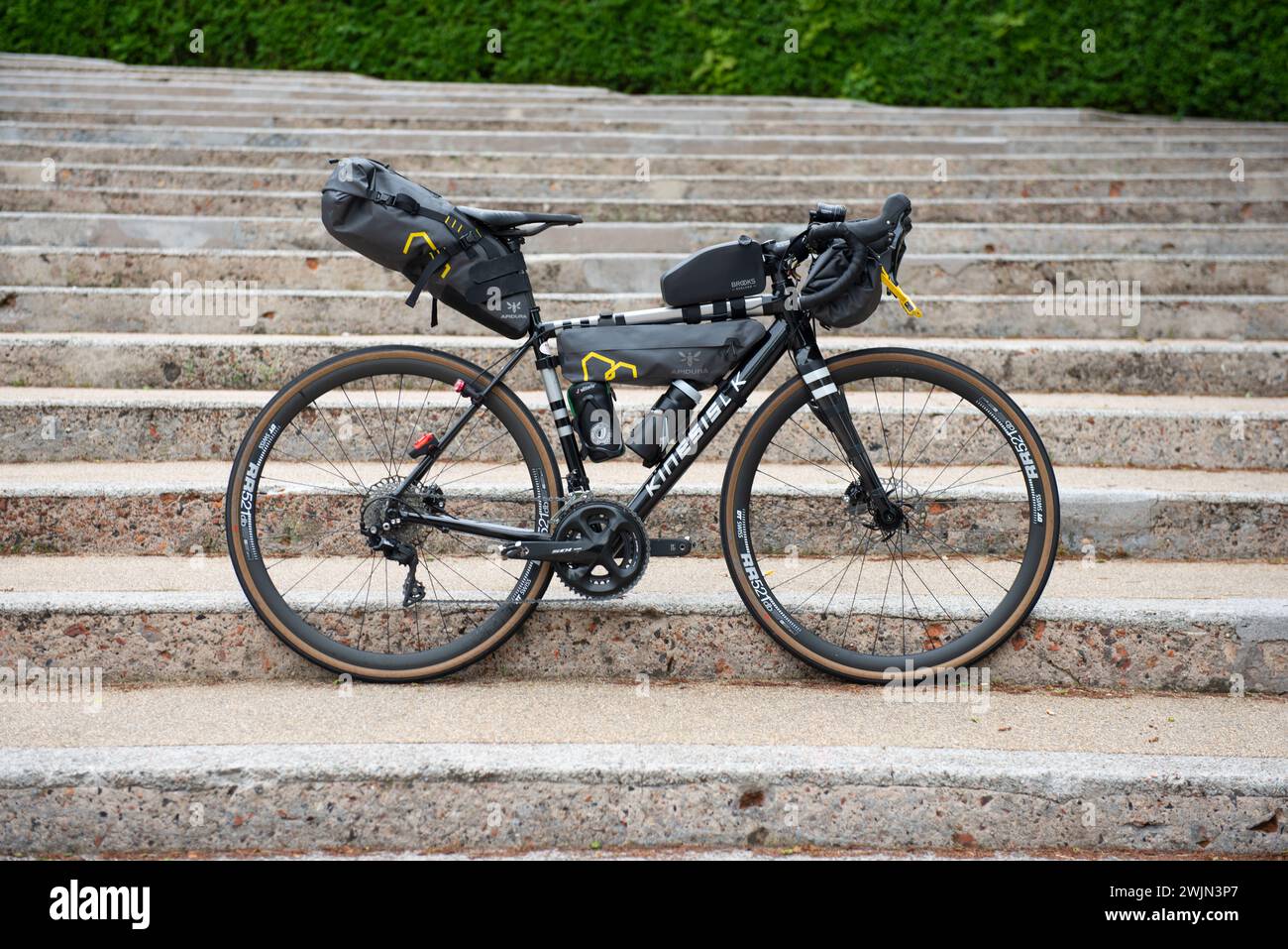 Ein Fahrrad-Tourenrad mit Taschen an Rahmen, Sattel und Lenker neigt sich gegen die aufsteigenden Stufen Stockfoto