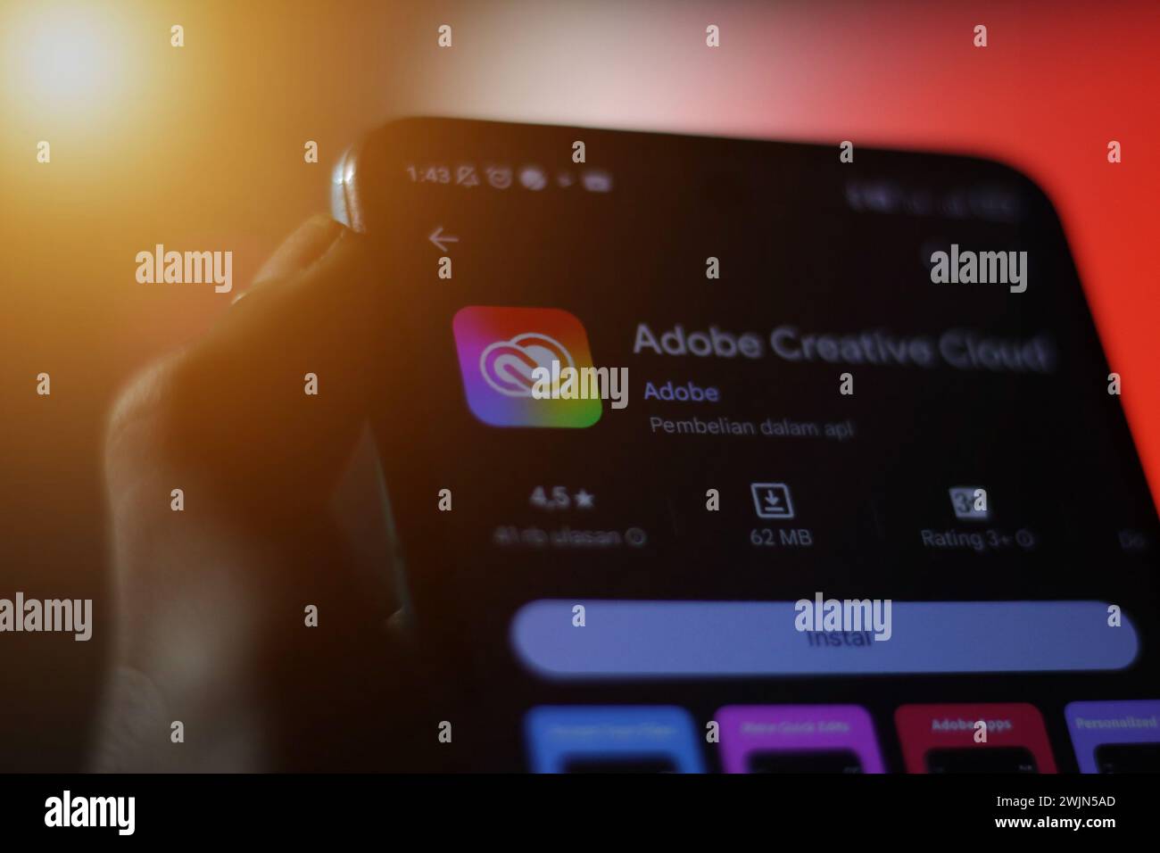 Die Hand eines Mannes, der ein Mobiltelefon mit adobe Creative Cloud Logo hält. Optischer Hintergrund. Editorial Stockfoto