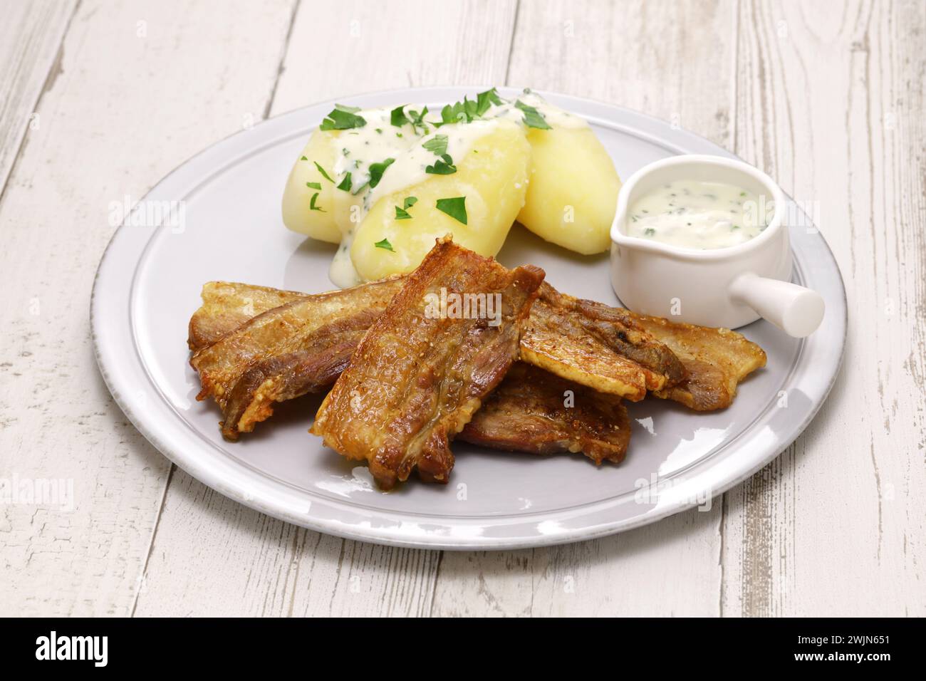 "Stegt flæsk med persillesovs" (Schweinebauch in Scheiben mit Haut und gebraten, serviert mit Petersiliensauce und gekochten Kartoffeln). Dänemarks Nationalkost. Stockfoto