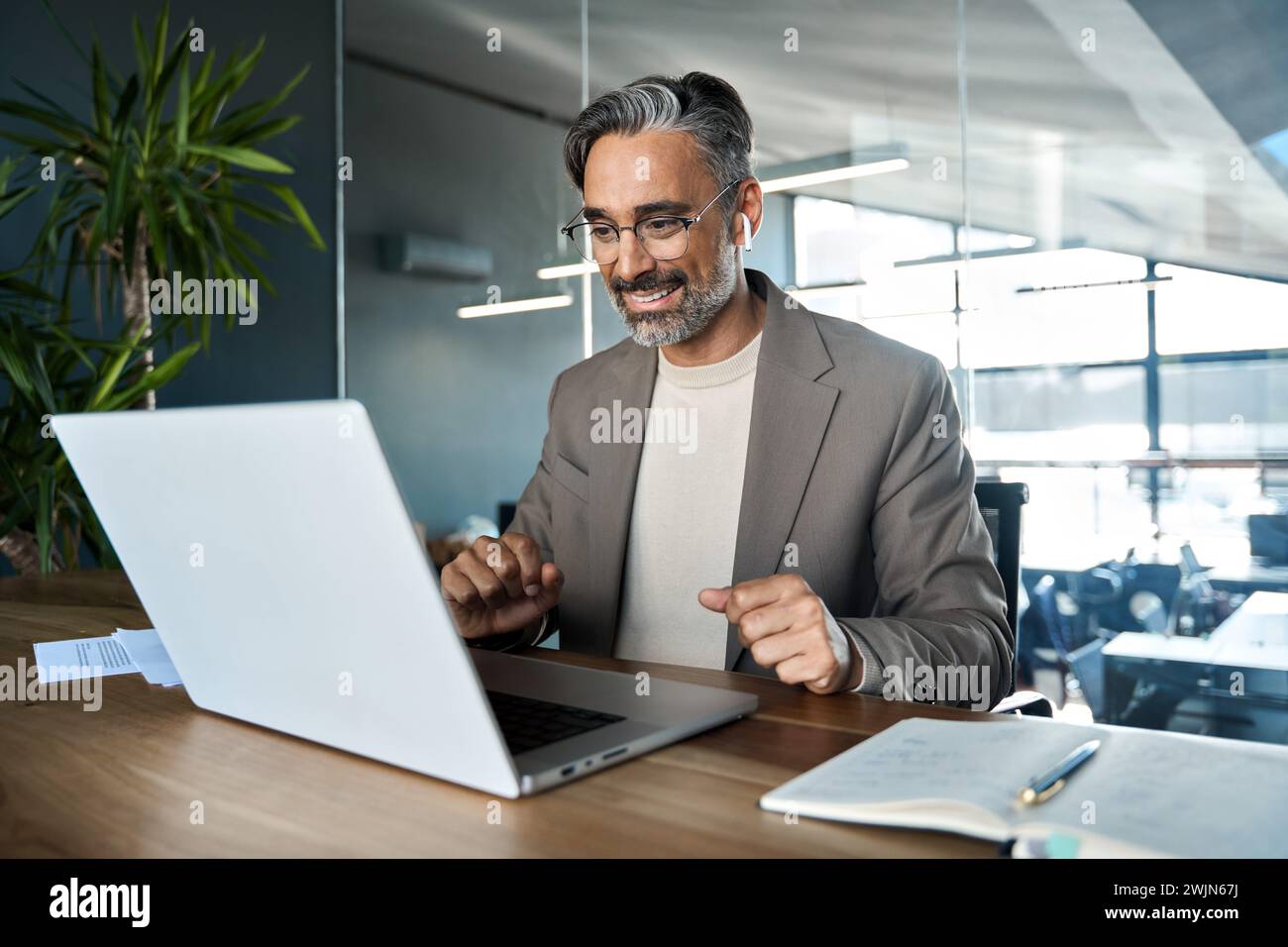 Reifer Geschäftsmann mit virtuellem Meeting zum Hybrid-Notebook im Büro. Stockfoto
