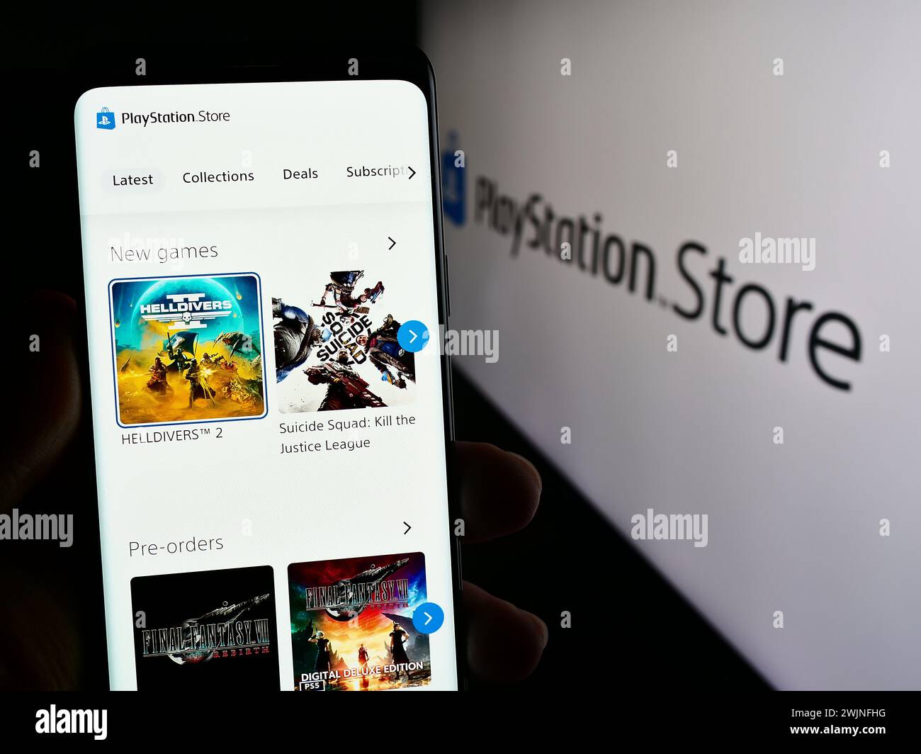 Person, die das Smartphone hält, mit der Webseite des Online-Online-Shops für Spiele im PlayStation Store (PS Store) vor dem Logo. Konzentrieren Sie sich auf die Mitte des Telefondisplays. Stockfoto