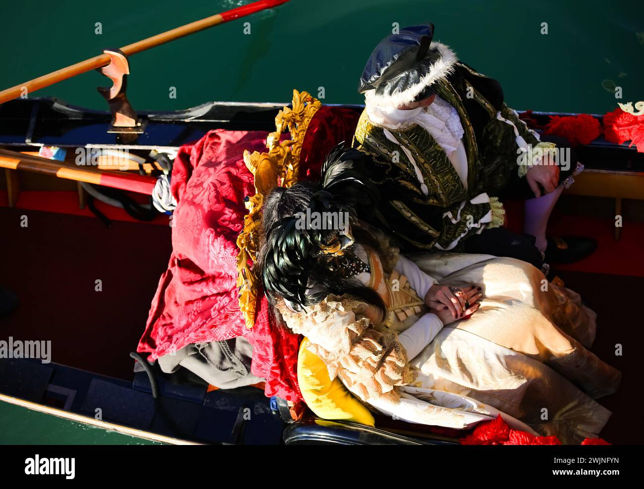 Venedig, VE, Italien - 13. Februar 2024: Verheiratetes Paar mit historischen Kostümen auf der Gondel während des venezianischen Karnevals Stockfoto
