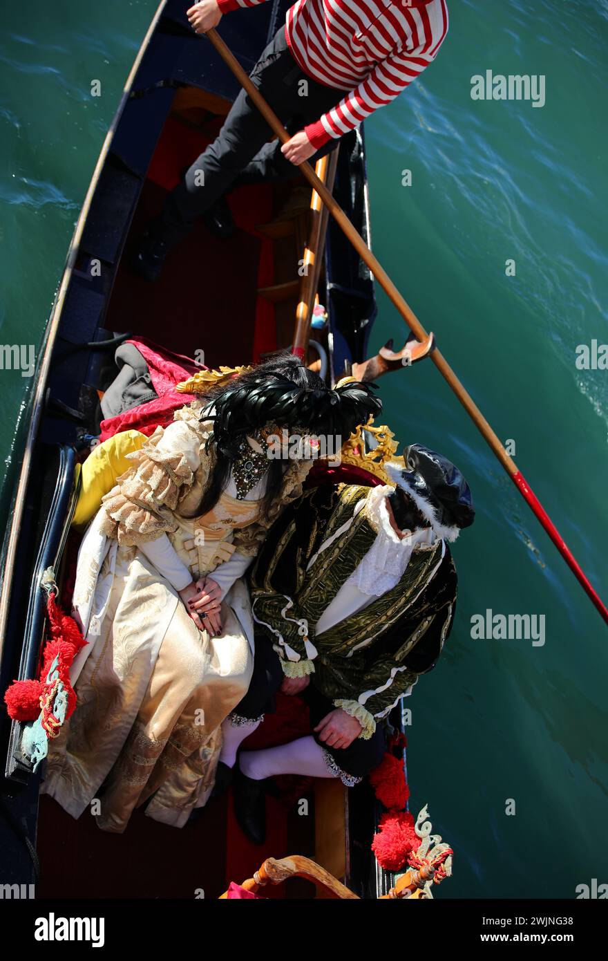 Venedig, VE, Italien - 13. Februar 2024: Verheiratetes Paar mit sehr luxuriösen historischen Kostümen auf der Gondel während des venezianischen Karnevals Stockfoto