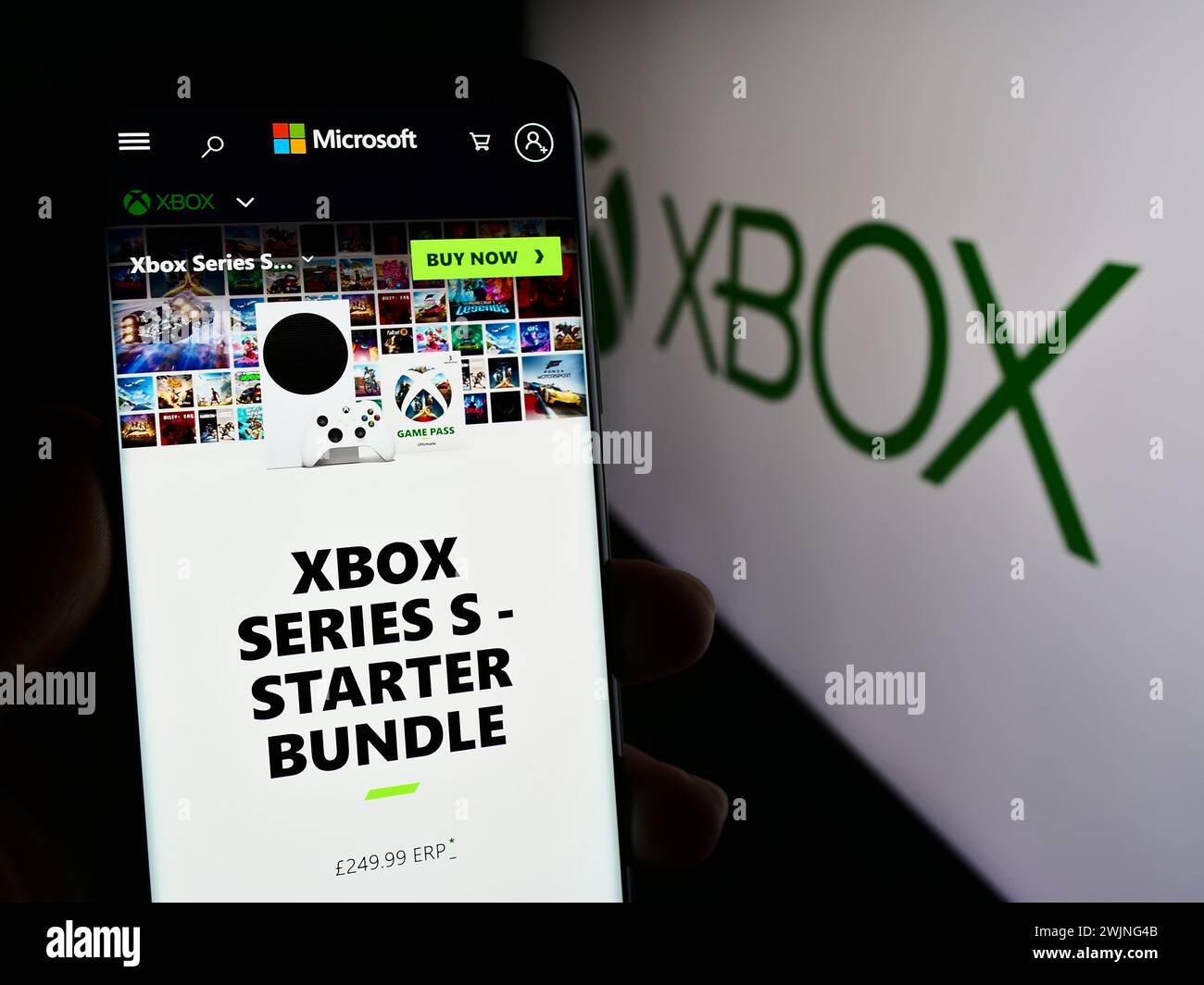 Person, die ein Mobiltelefon hält, mit der Webseite der Videospielkonsole Xbox (Microsoft) vor dem Firmenlogo. Konzentrieren Sie sich auf die Mitte des Telefondisplays. Stockfoto